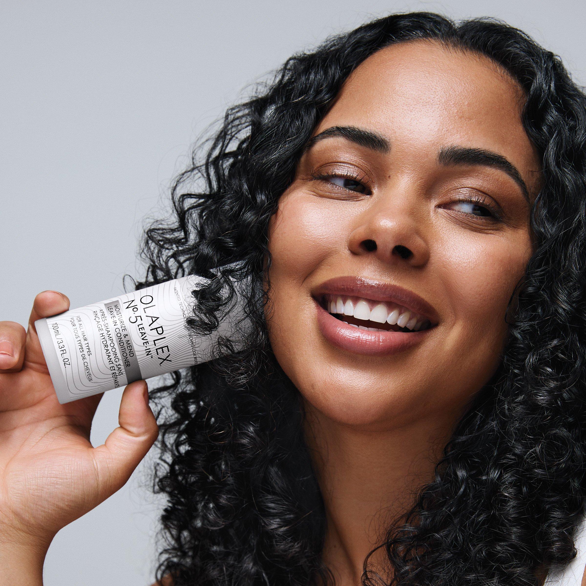 Olaplex bottle being held by a black haried woman smiling