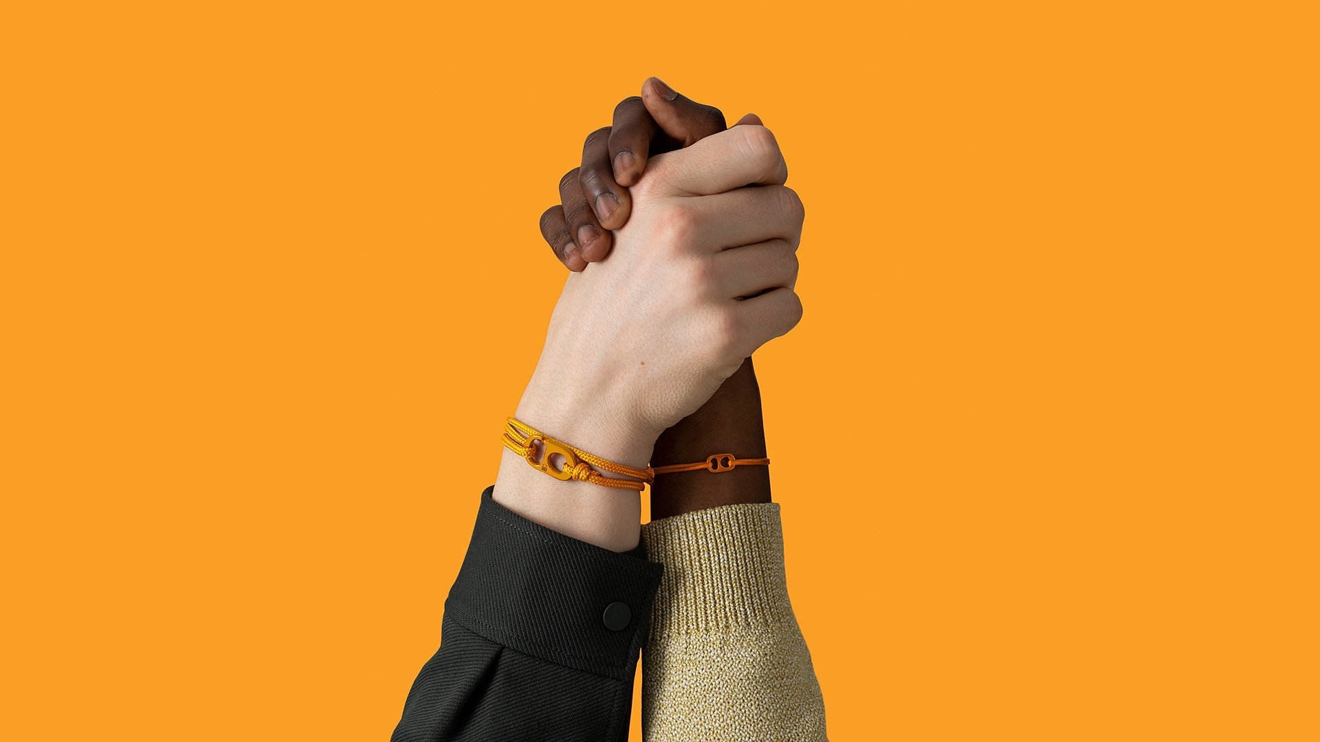 Two hands on a yellow background wearing #TOGETHERBANDs