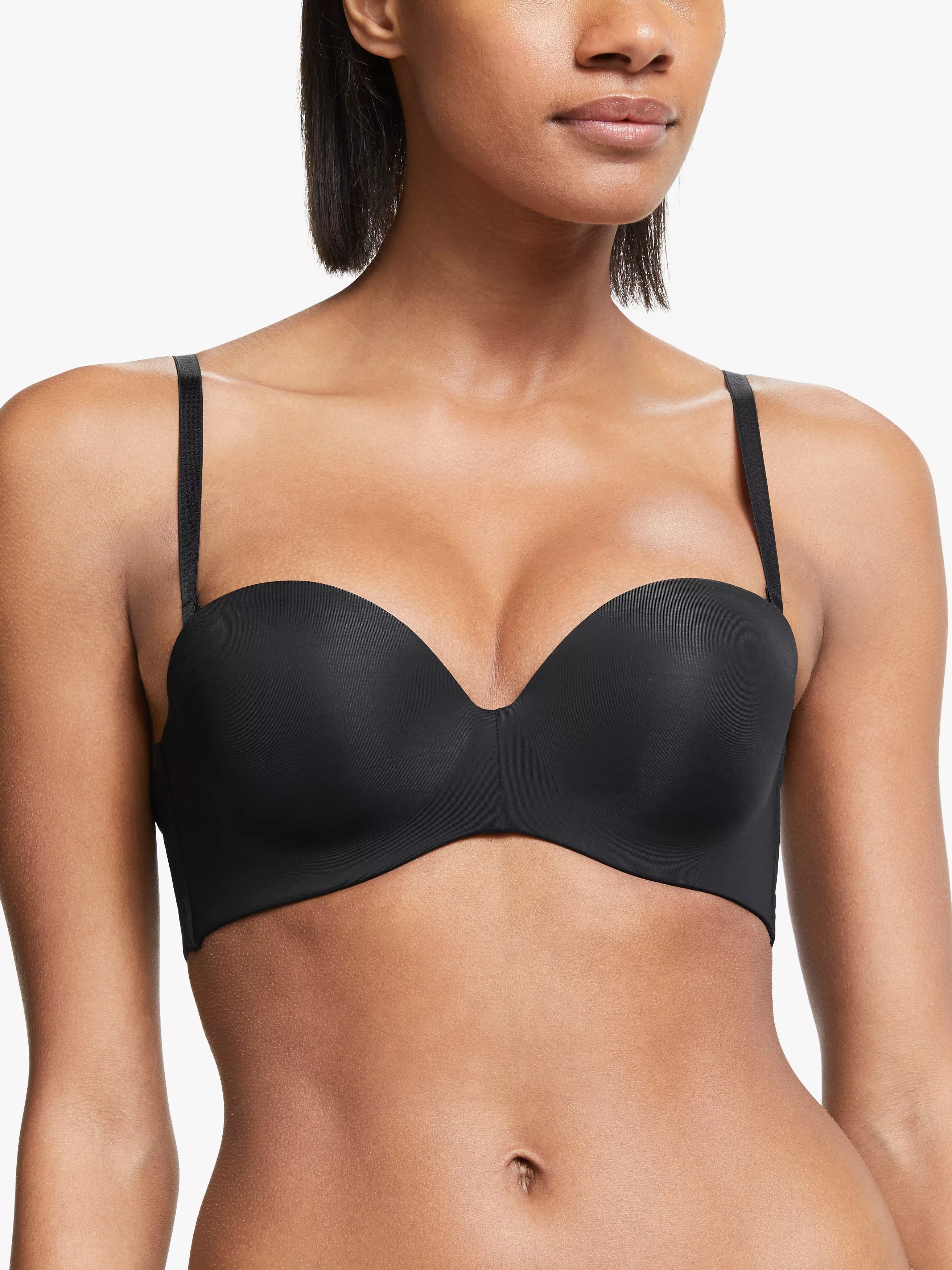 Woman wearing a sleek black strapless bra with thin straps, showcasing a seamless design against a white background.
