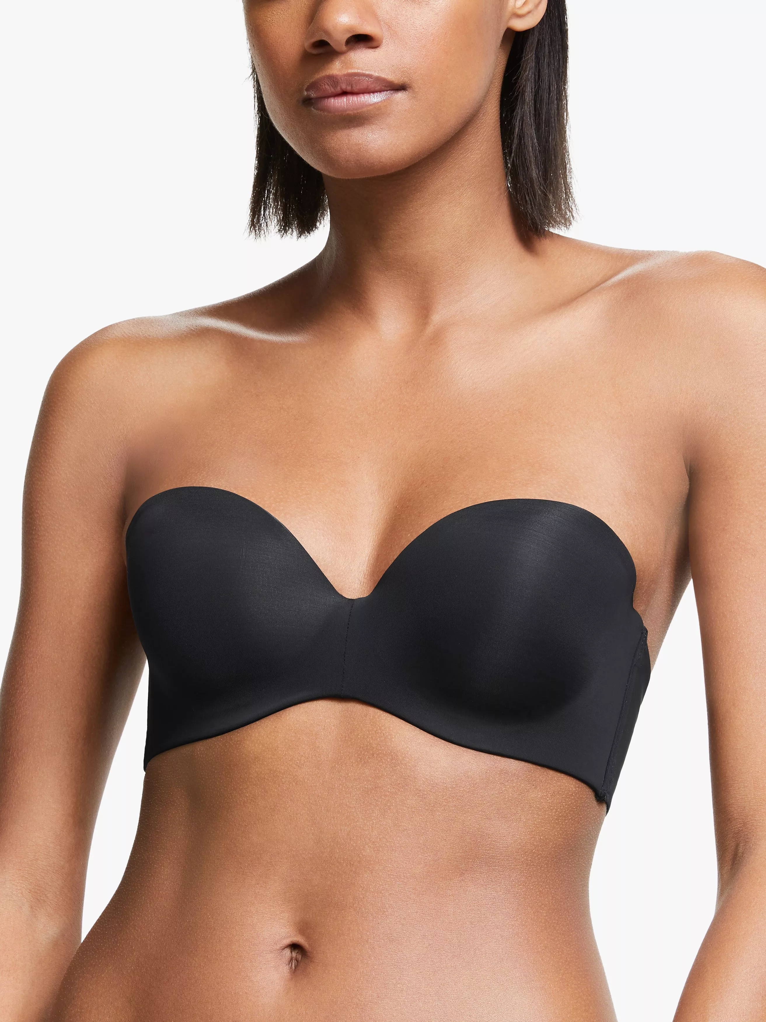 Model wearing a black strapless balconette bra with smooth moulded cups, shown in a studio close-up on white background