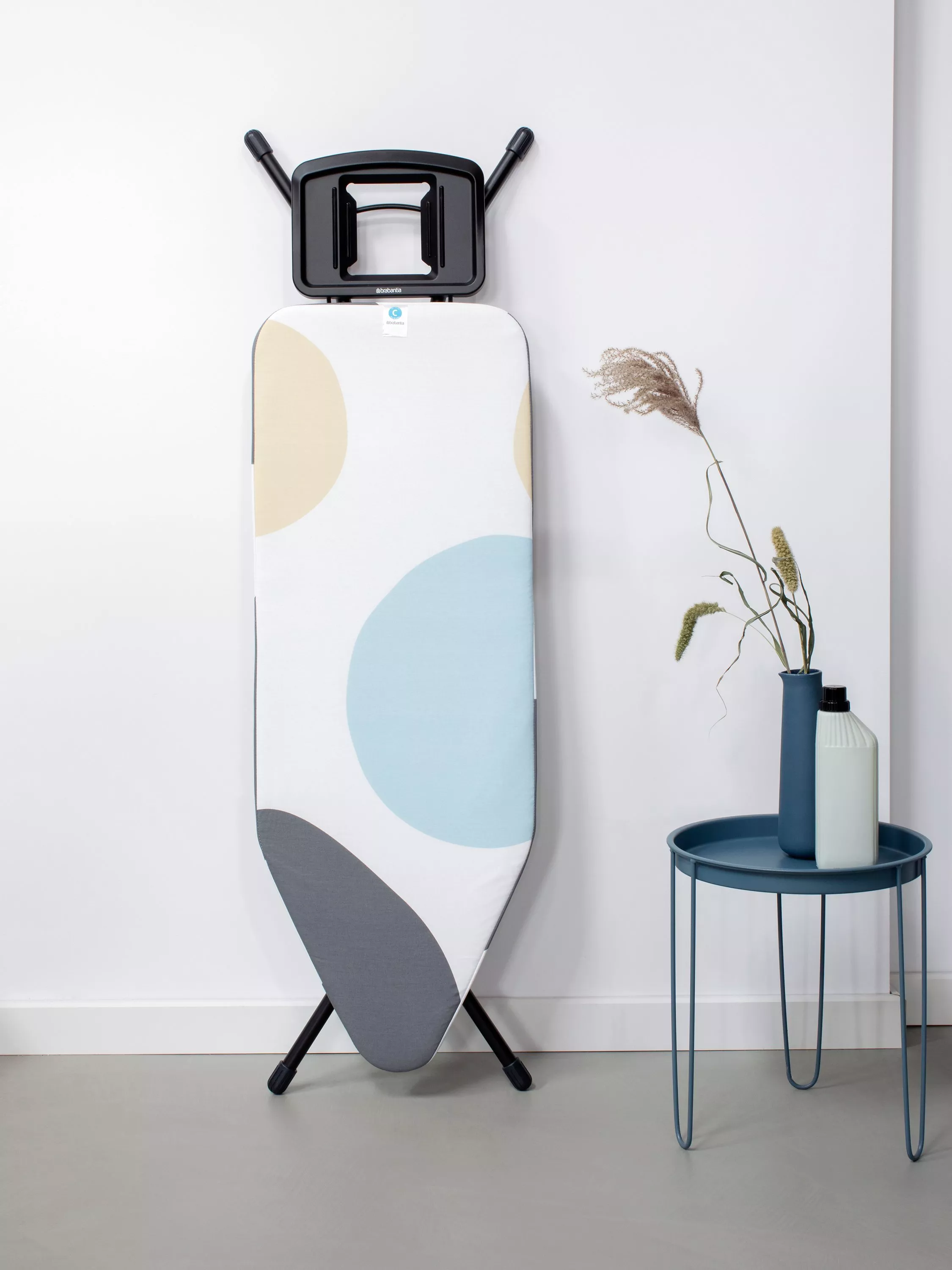 Modern ironing board cover with blue, mustard and grey circle pattern on white background, top view