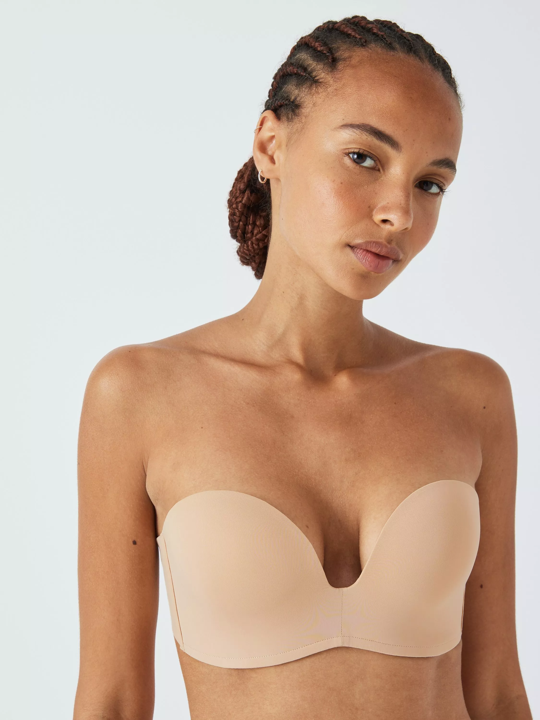 Studio close-up of model wearing nude strapless plunge bra, smooth supportive lingerie 