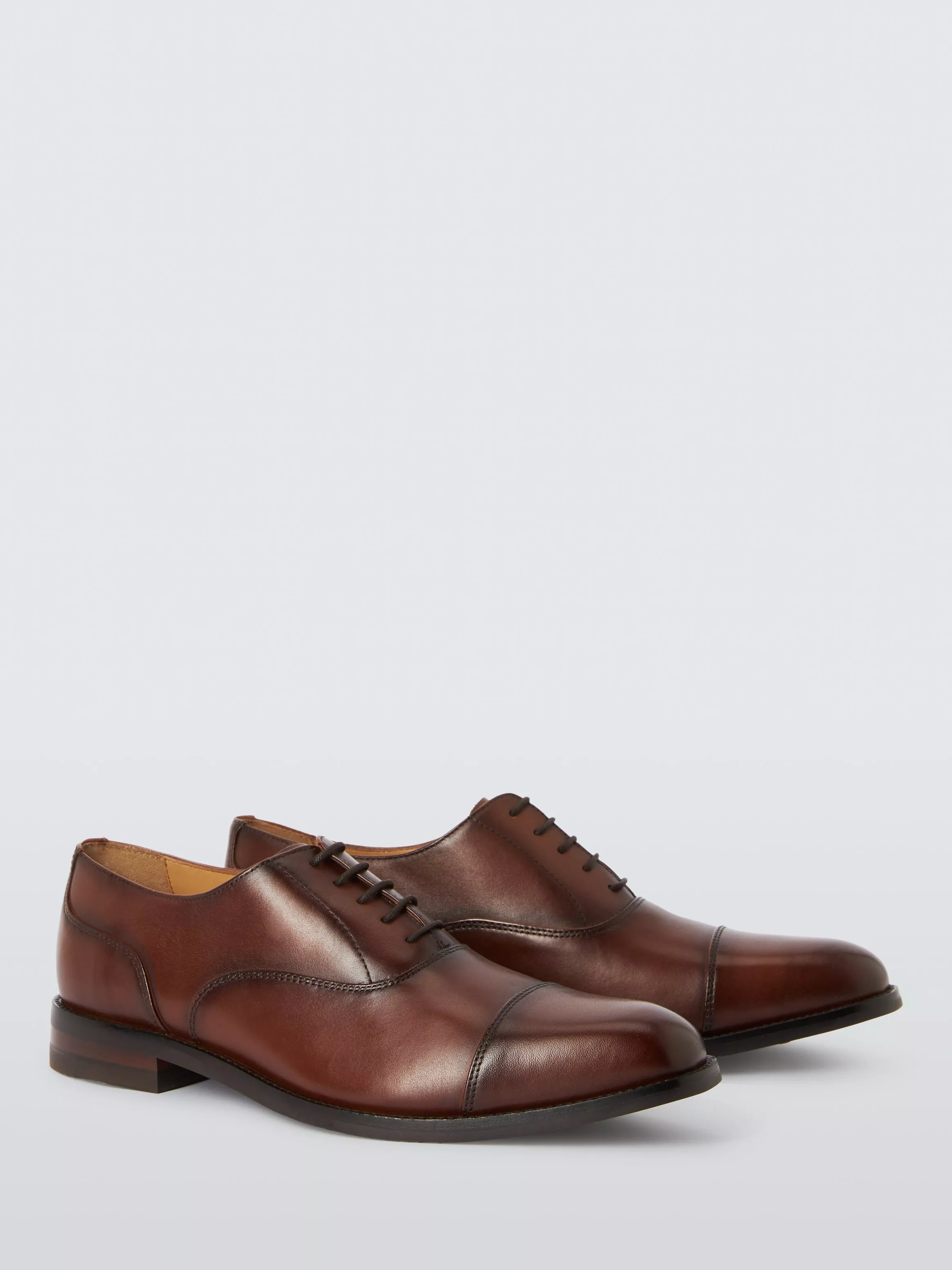 Pair of brown leather Oxford dress shoes with cap toe, lace-up design, on light grey studio background