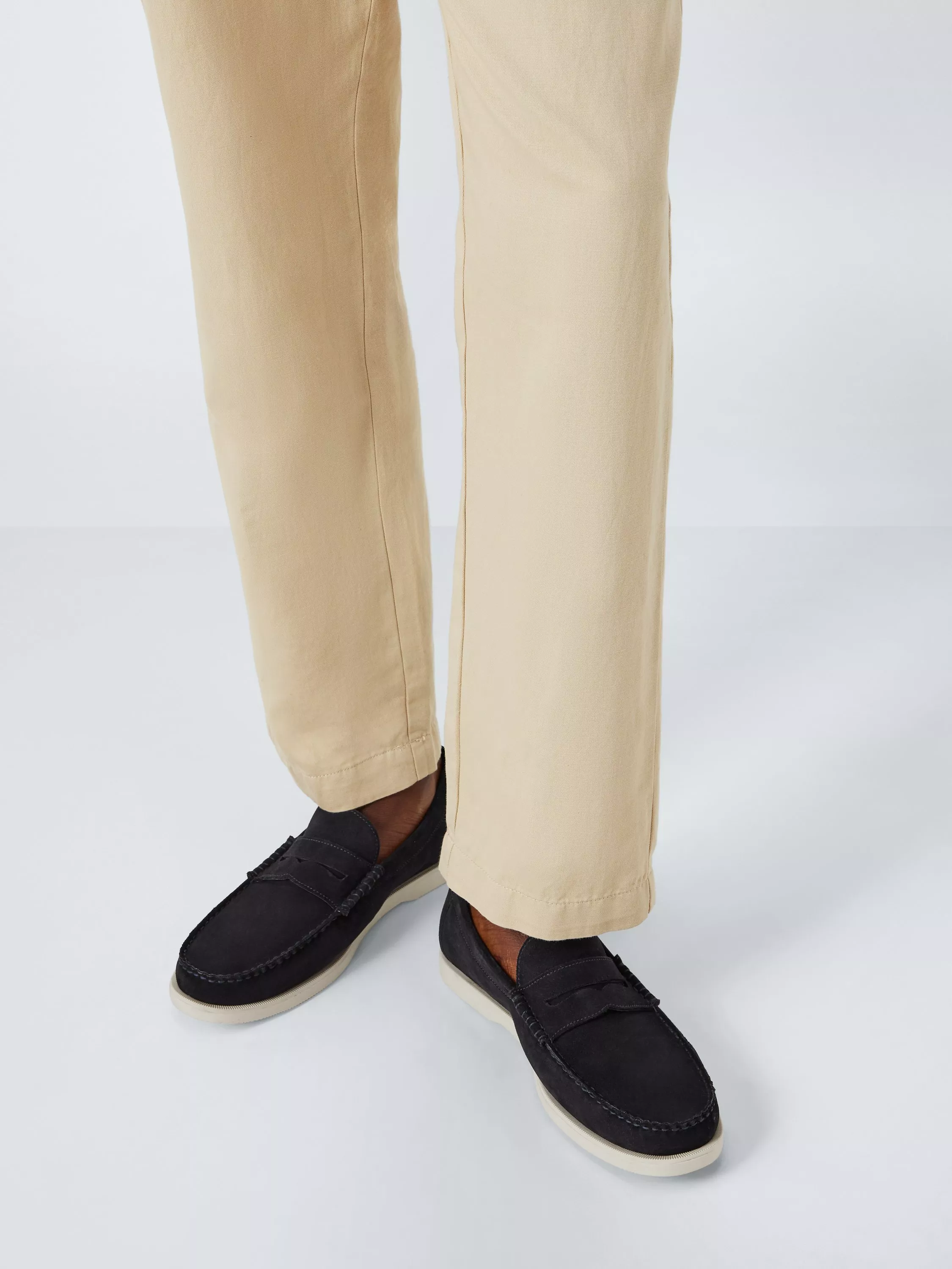 Beige chinos with black leather loafers, men’s smart casual trousers and slip-on shoes on white background