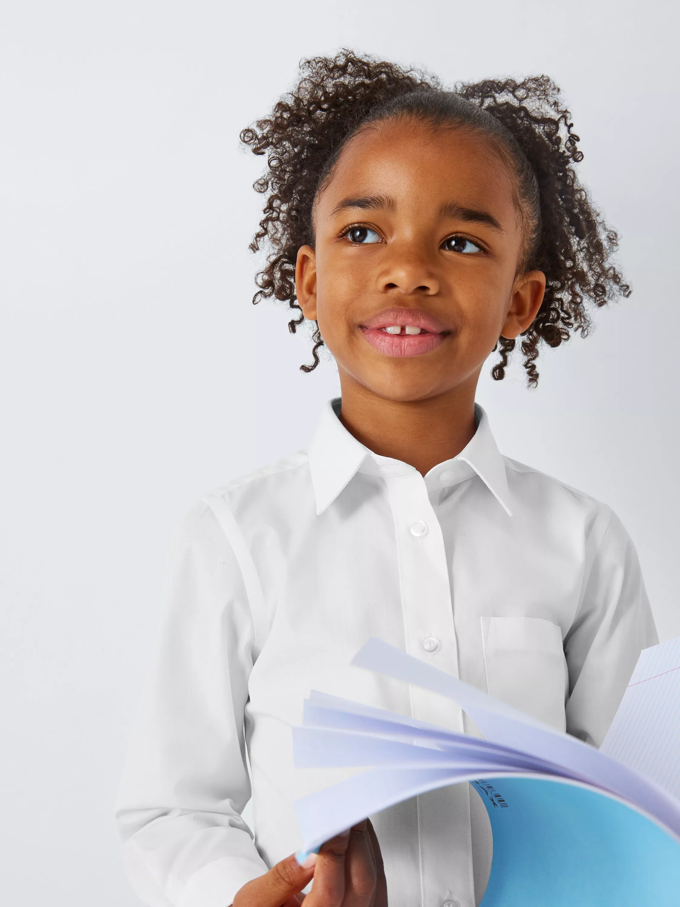 Smiling schoolgirl in white button-up shirt and black trousers, studio portrait on clean white background