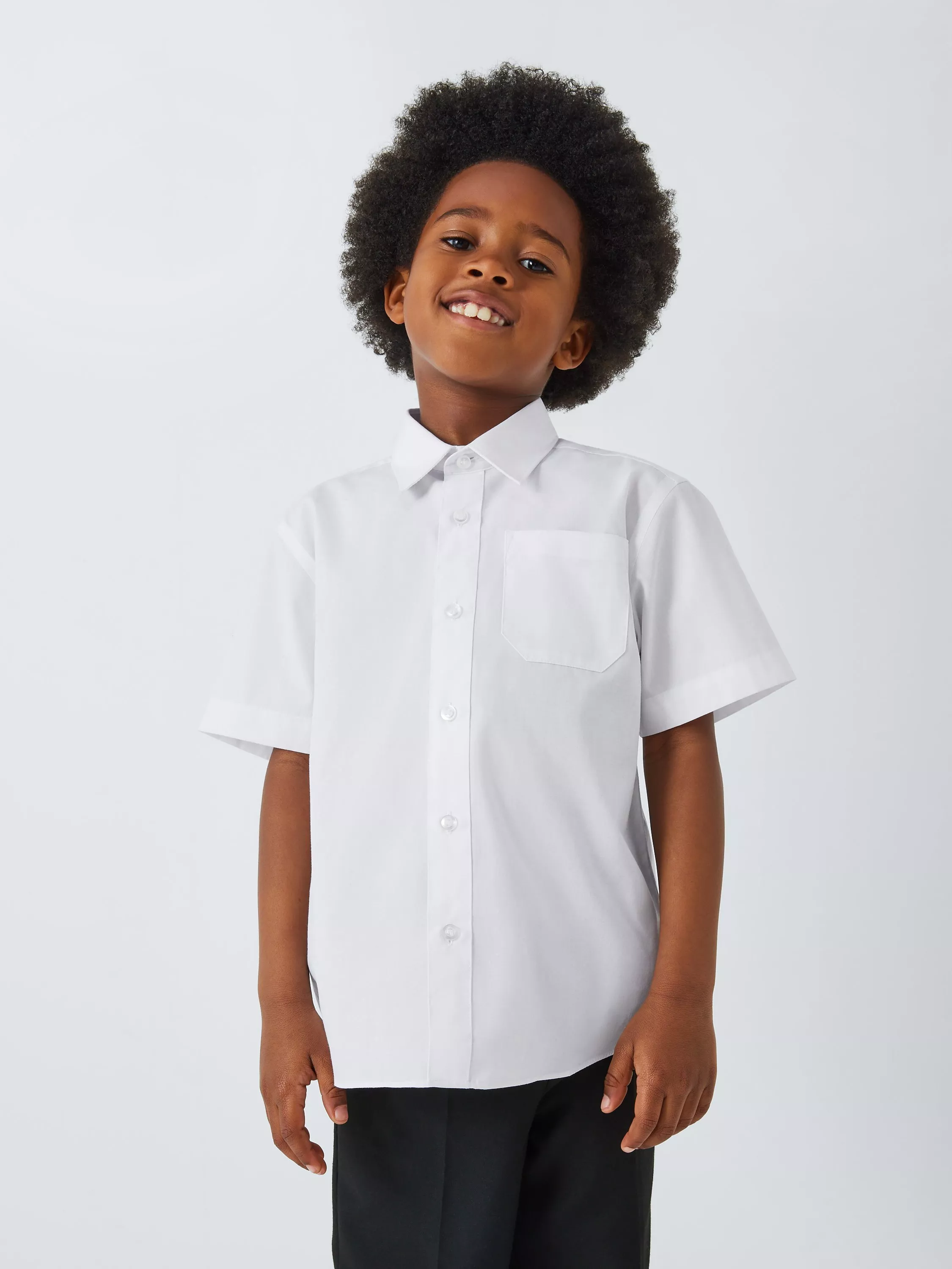 Child wearing white short-sleeve school shirt with chest pocket and black trousers on studio background