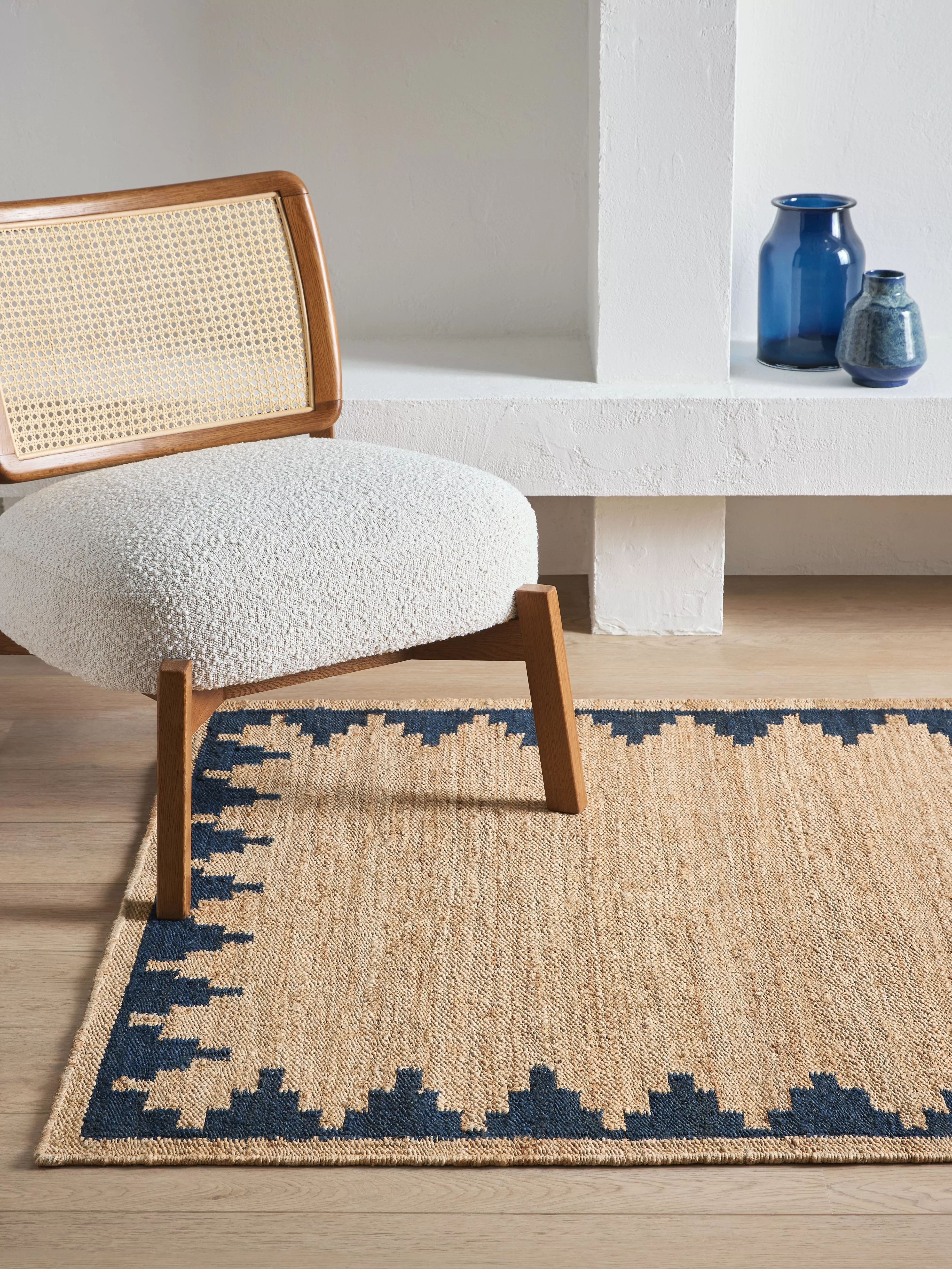 Red leather cushion on blue woven rug, top-down view with textured grey fabric border in modern home décor