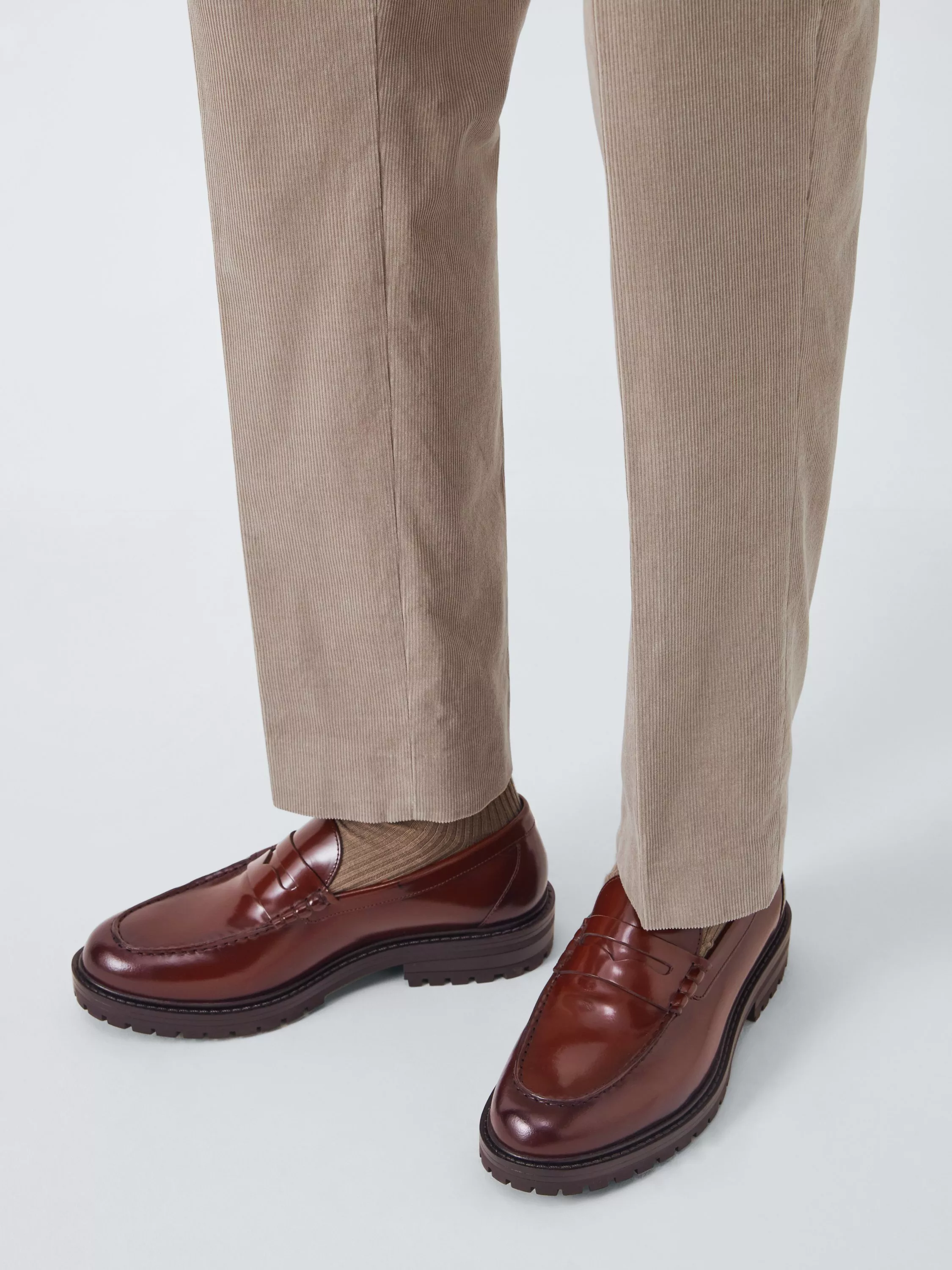 man wearing brown patent loafers and beige tailored trousers