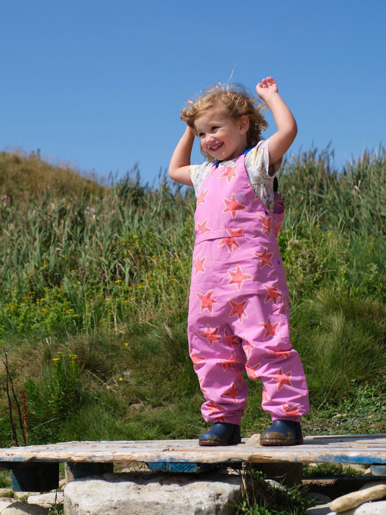 Product image 3 of 6, which shows Muddy Puddles Kids' EcoLight Waterproof Lightweight Star Dungarees, Pink/Multi, 12-18 months
