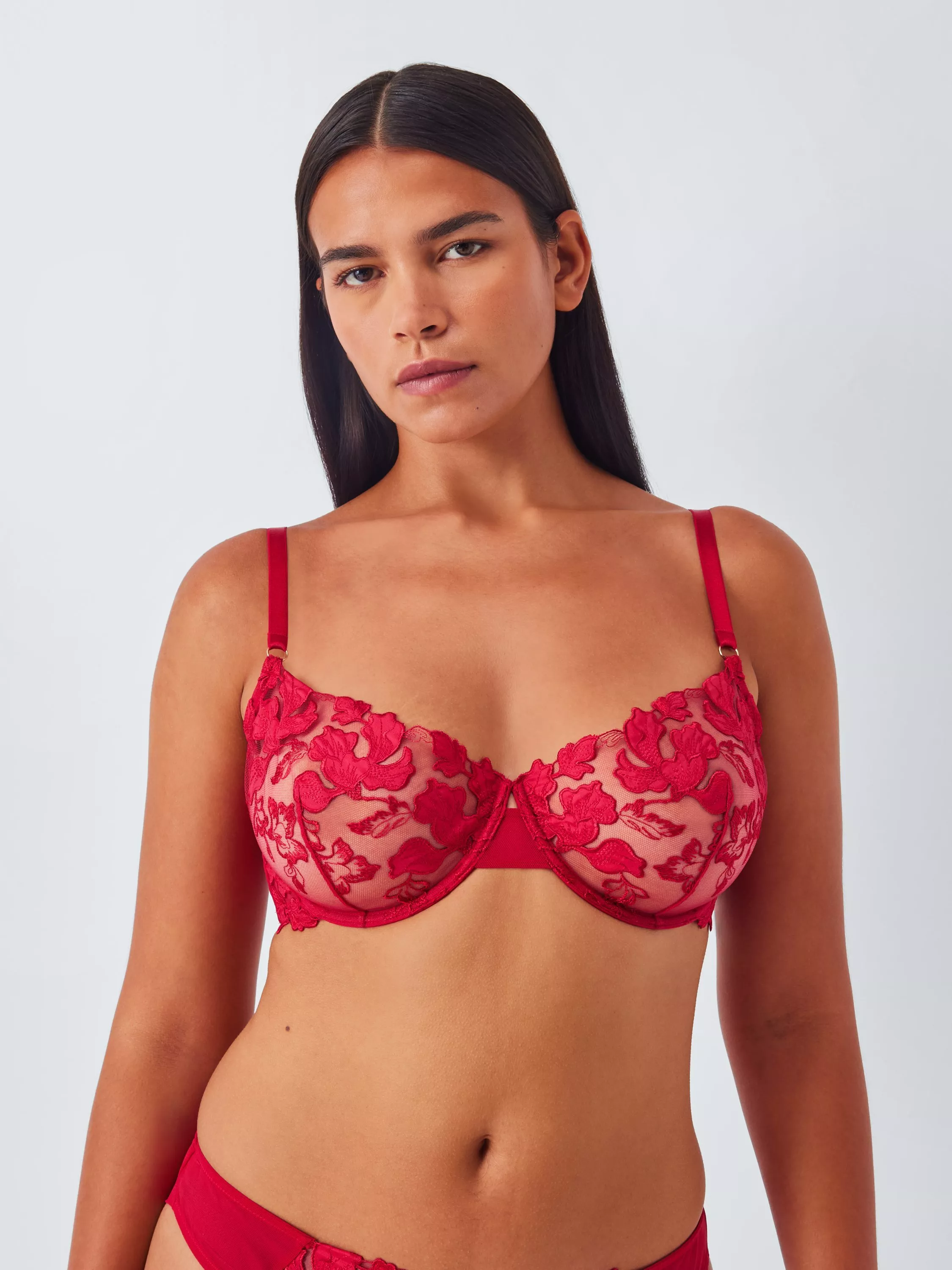 Model wearing red floral lace underwired bra and matching briefs, lingerie set on a light studio background