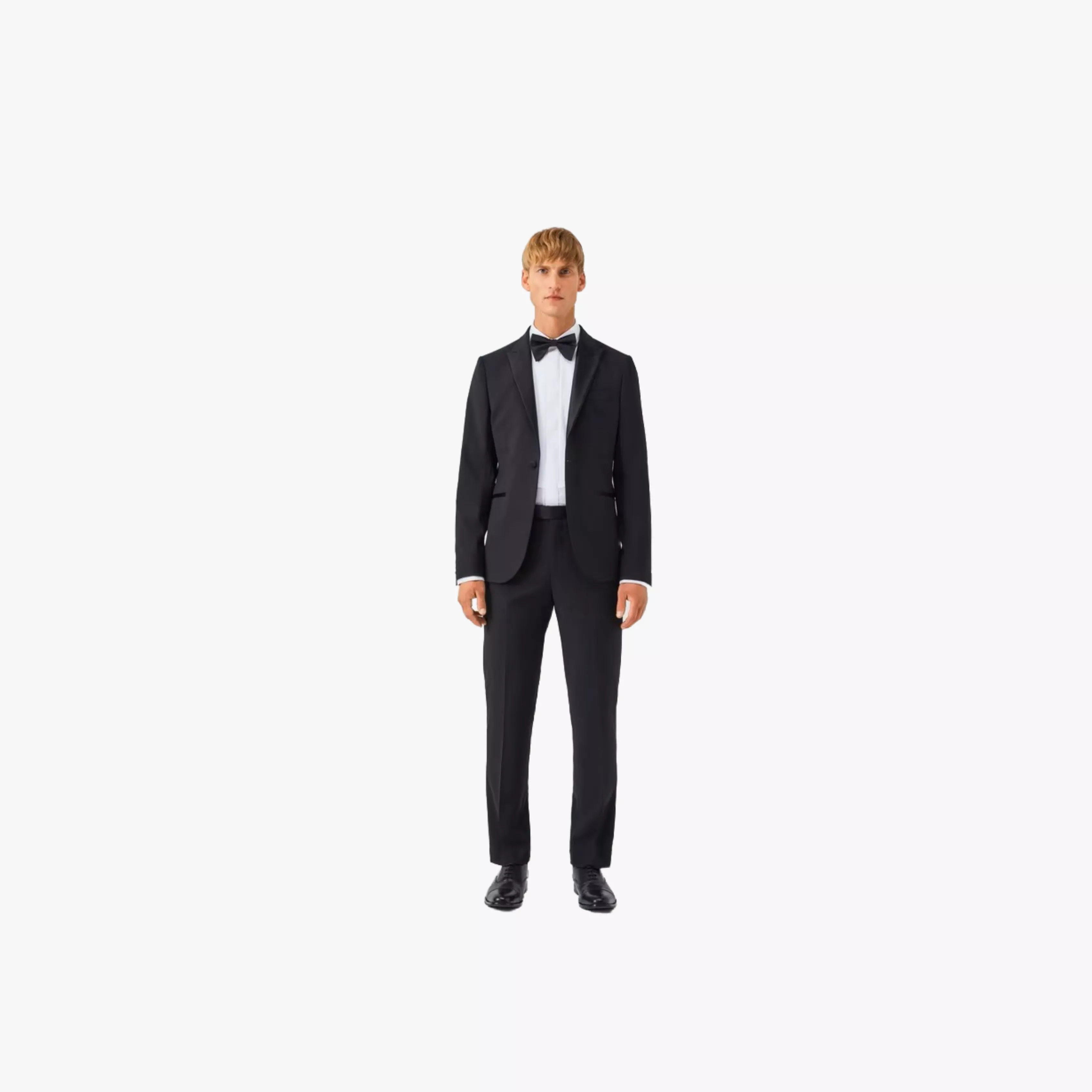 Full-length studio photo of a man wearing a navy business suit, striped tie and black dress shoes on white background