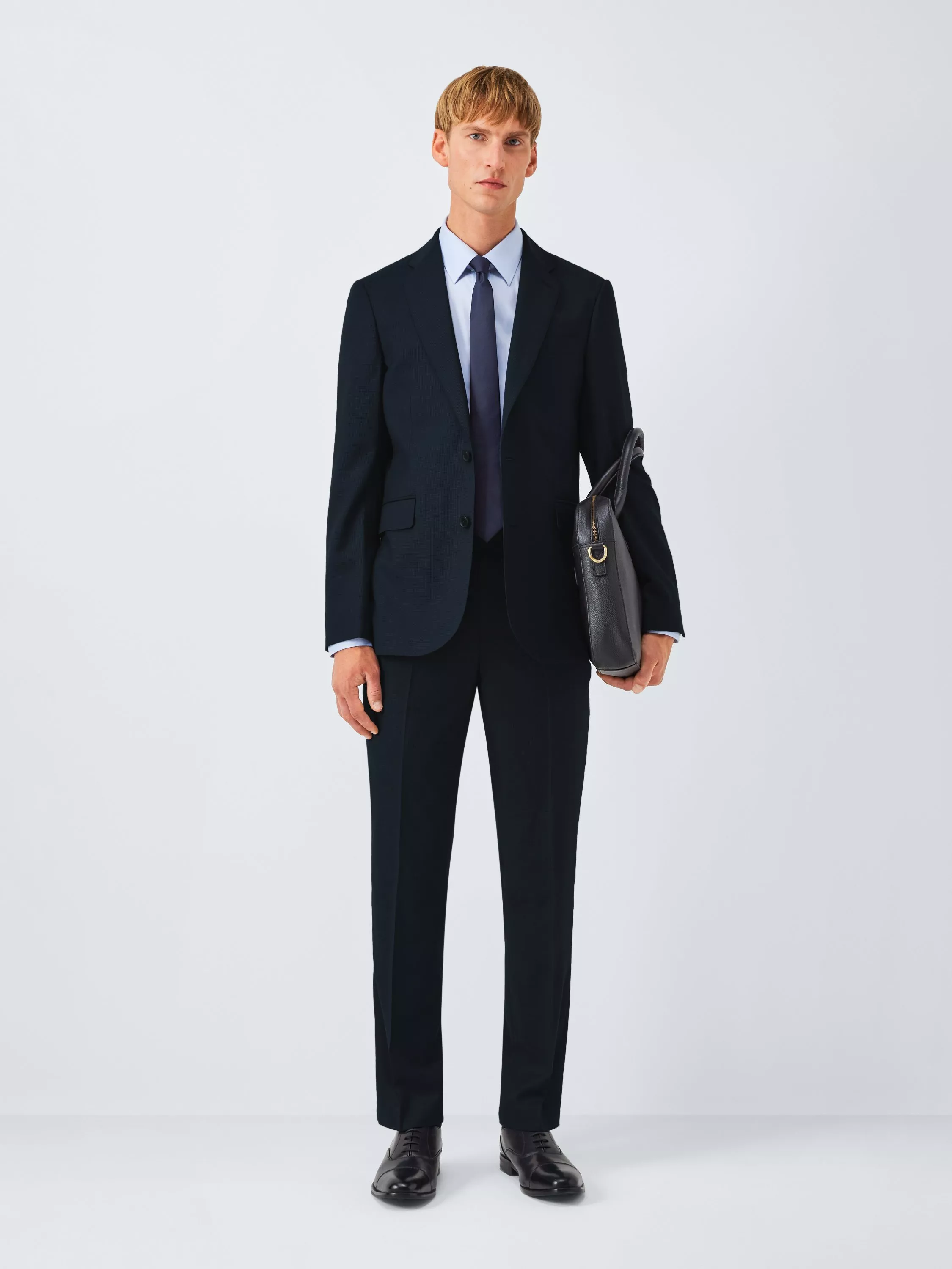 Full-length man in navy business suit with tie, holding leather briefcase, formal office wear on white background
