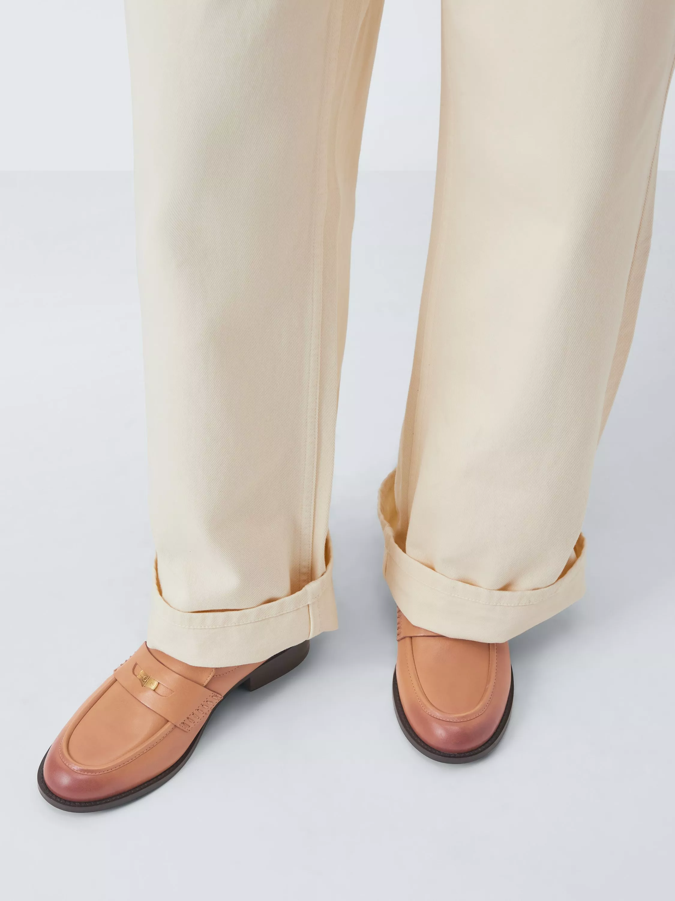 Stylish black leather loafers paired with dark leather trousers, showcasing modern fashion footwear.