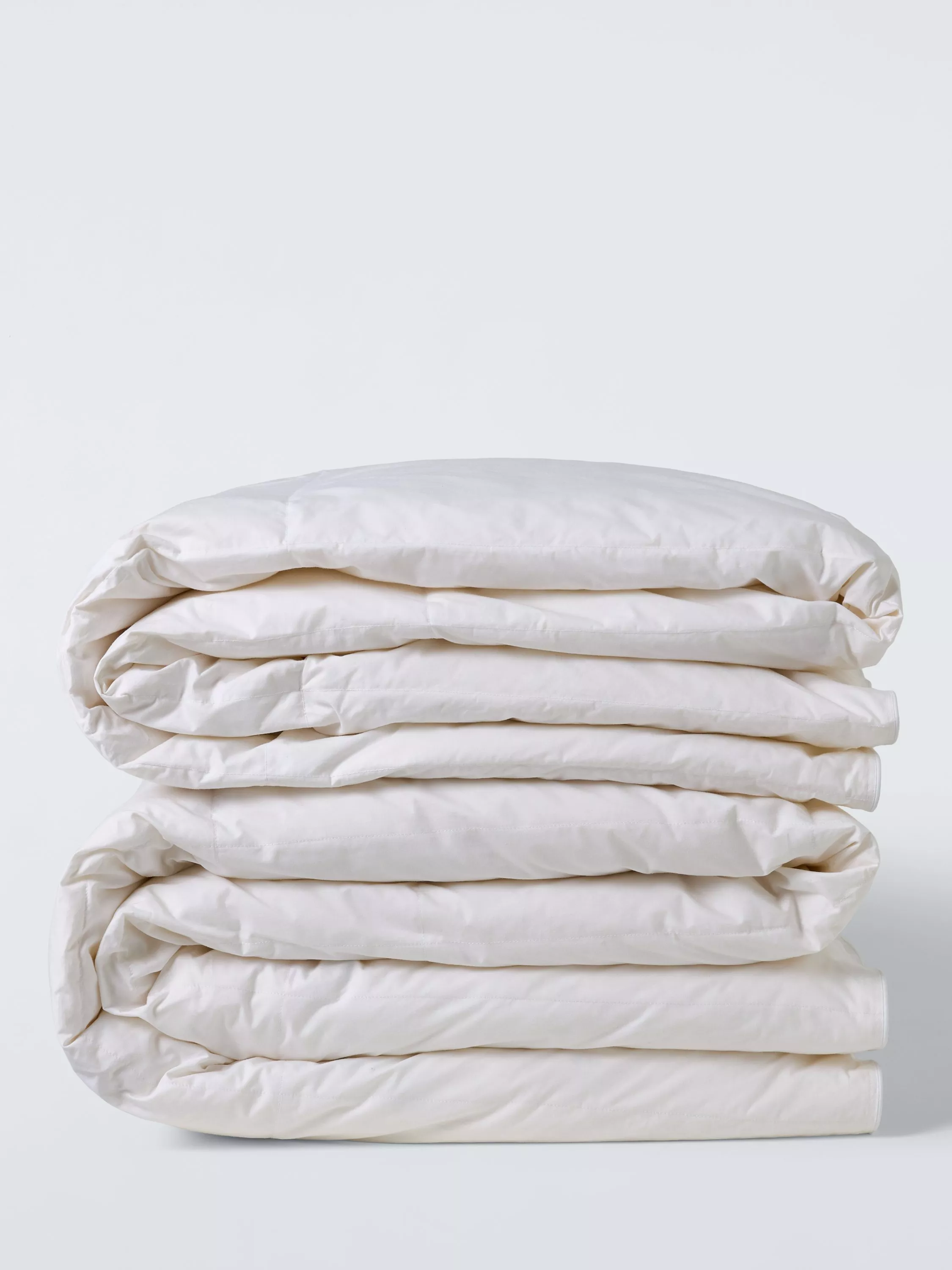 Stacked white cotton duvet and bedding set folded neatly on a clean light background, minimalist home textiles photo