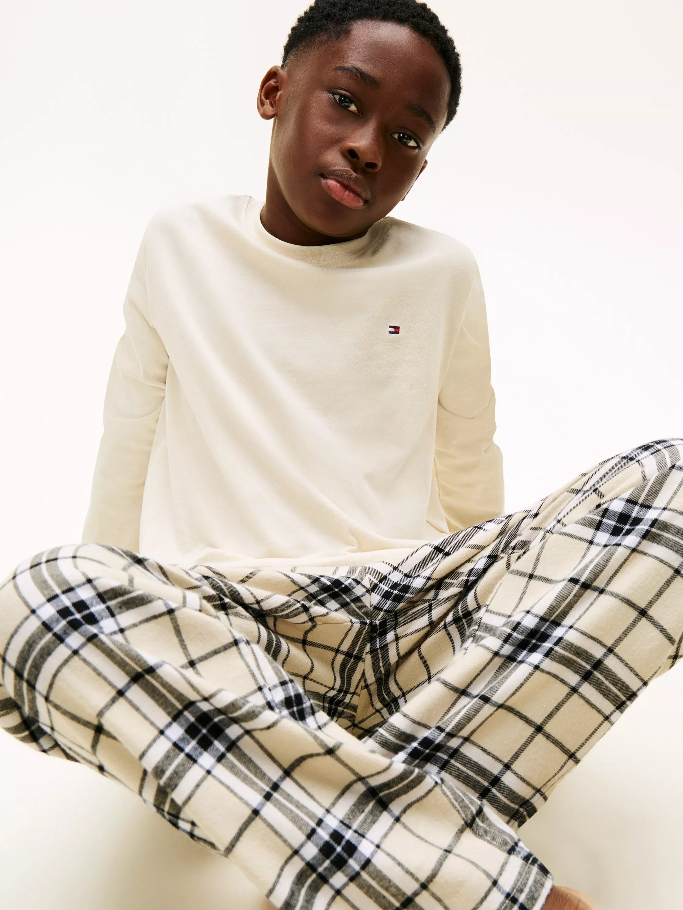 boy wearing a cream pyjama top with checked pyjama bottoms