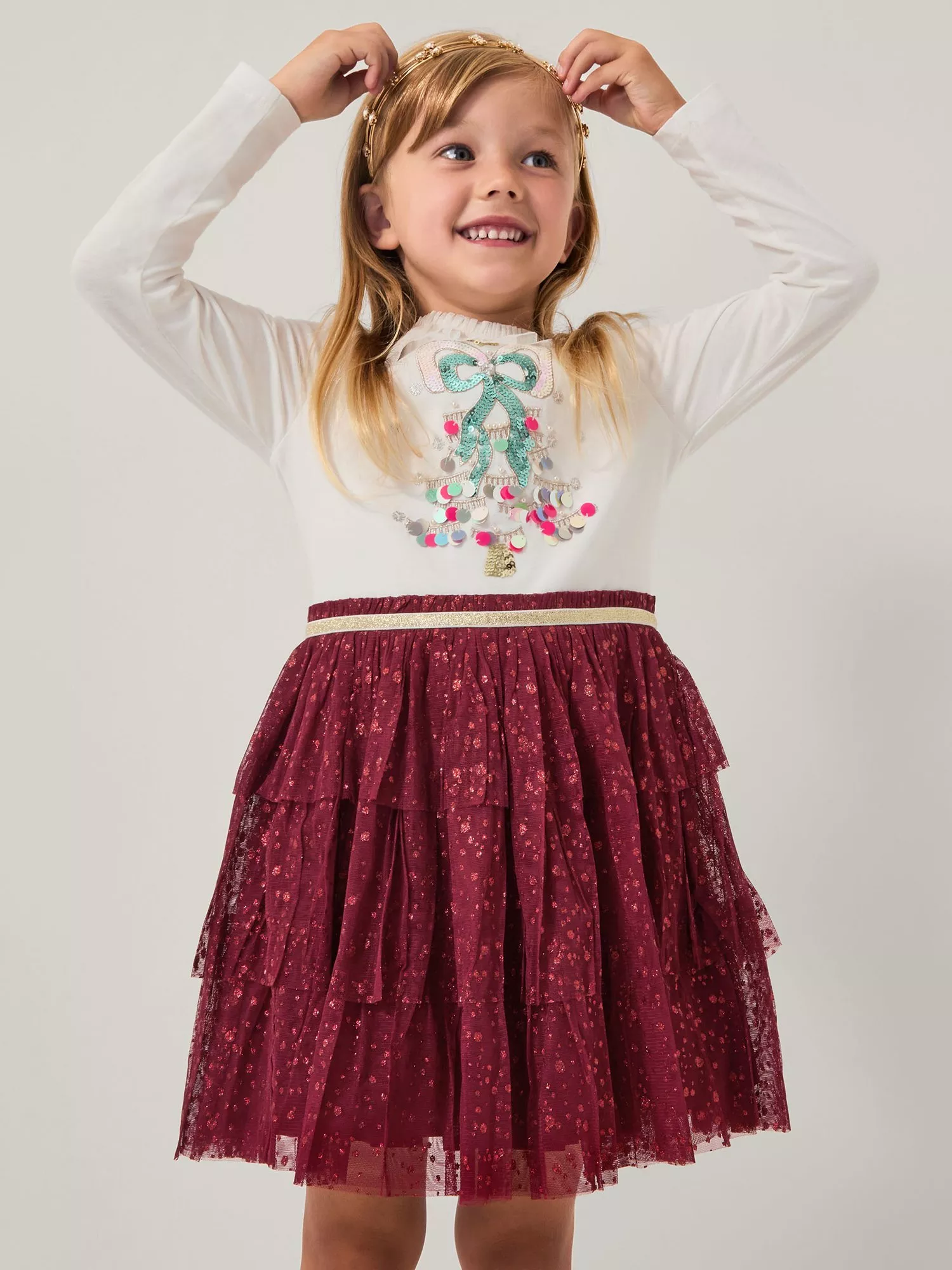 girl wearing a dress with a Christmas tree on it and a red sequin skirt