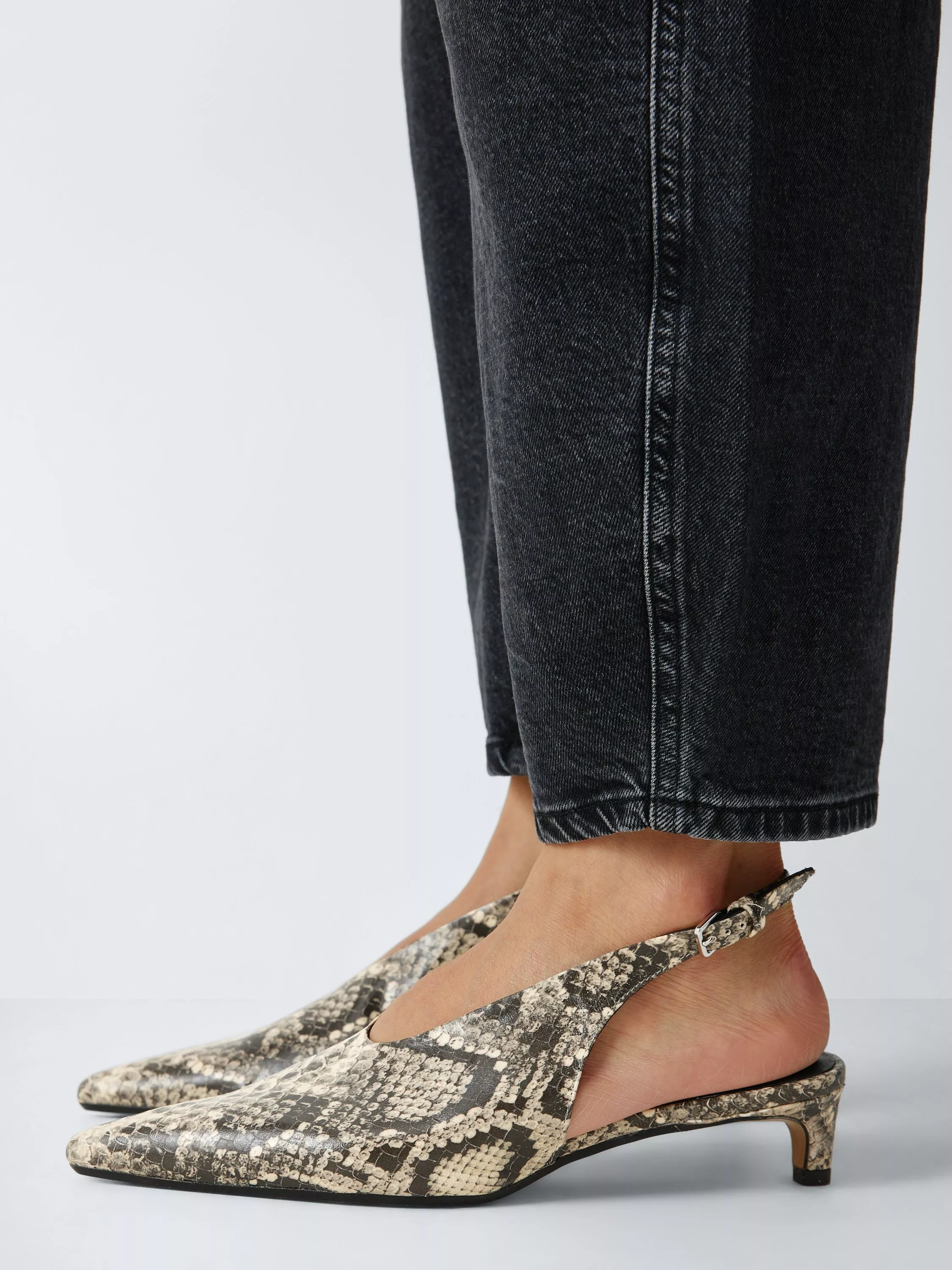 Close-up of slingback kitten heels in snakeskin print with black jeans, modern women’s footwear detail shot