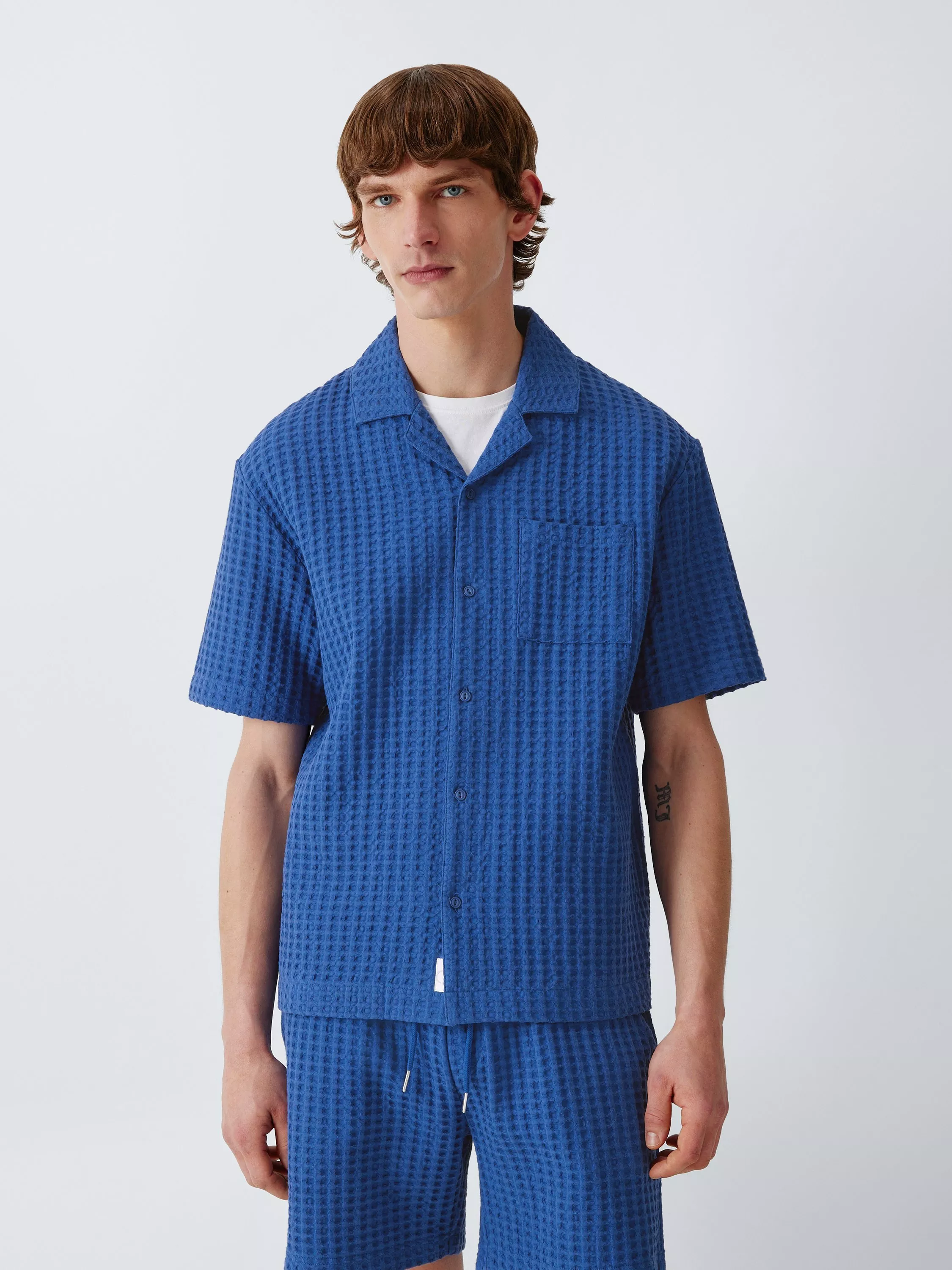 Men’s blue waffle-texture short-sleeve button-up shirt and matching shorts co-ord set, studio portrait