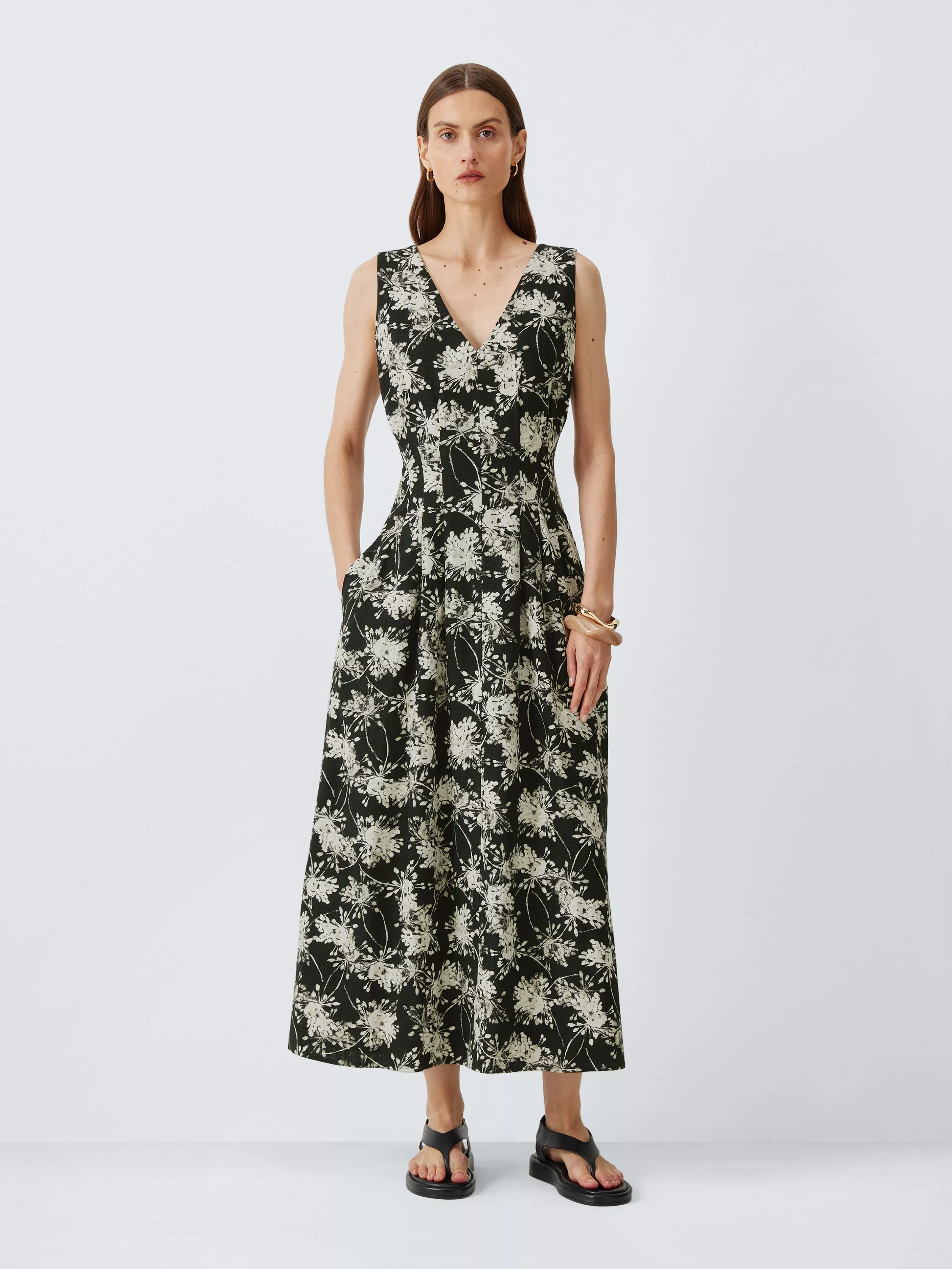 Model wearing black and white floral V-neck sleeveless midi dress with pockets, styled with black sandals