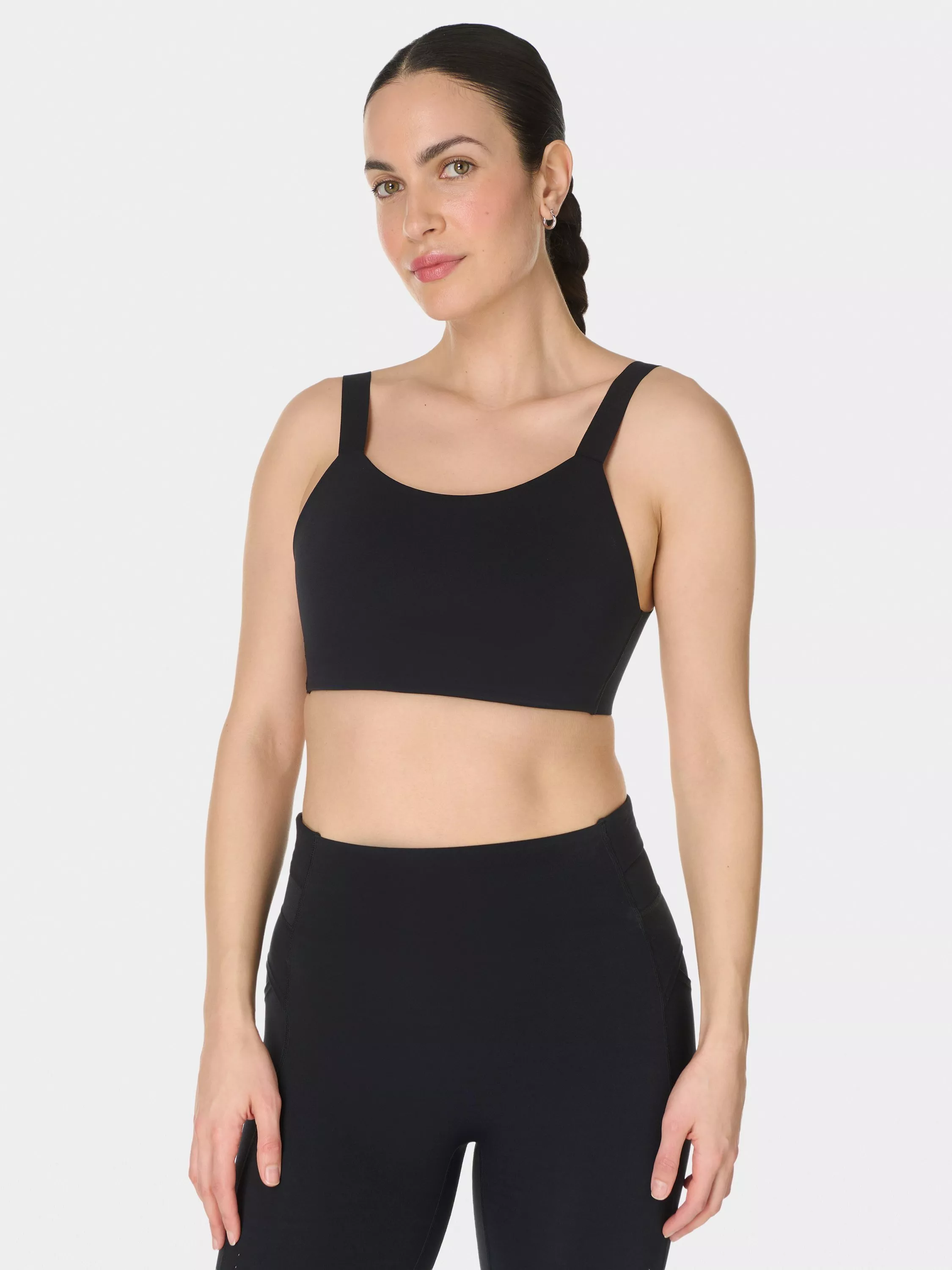 Model wearing black Under Armour sports bra with adjustable straps and branded elastic underband