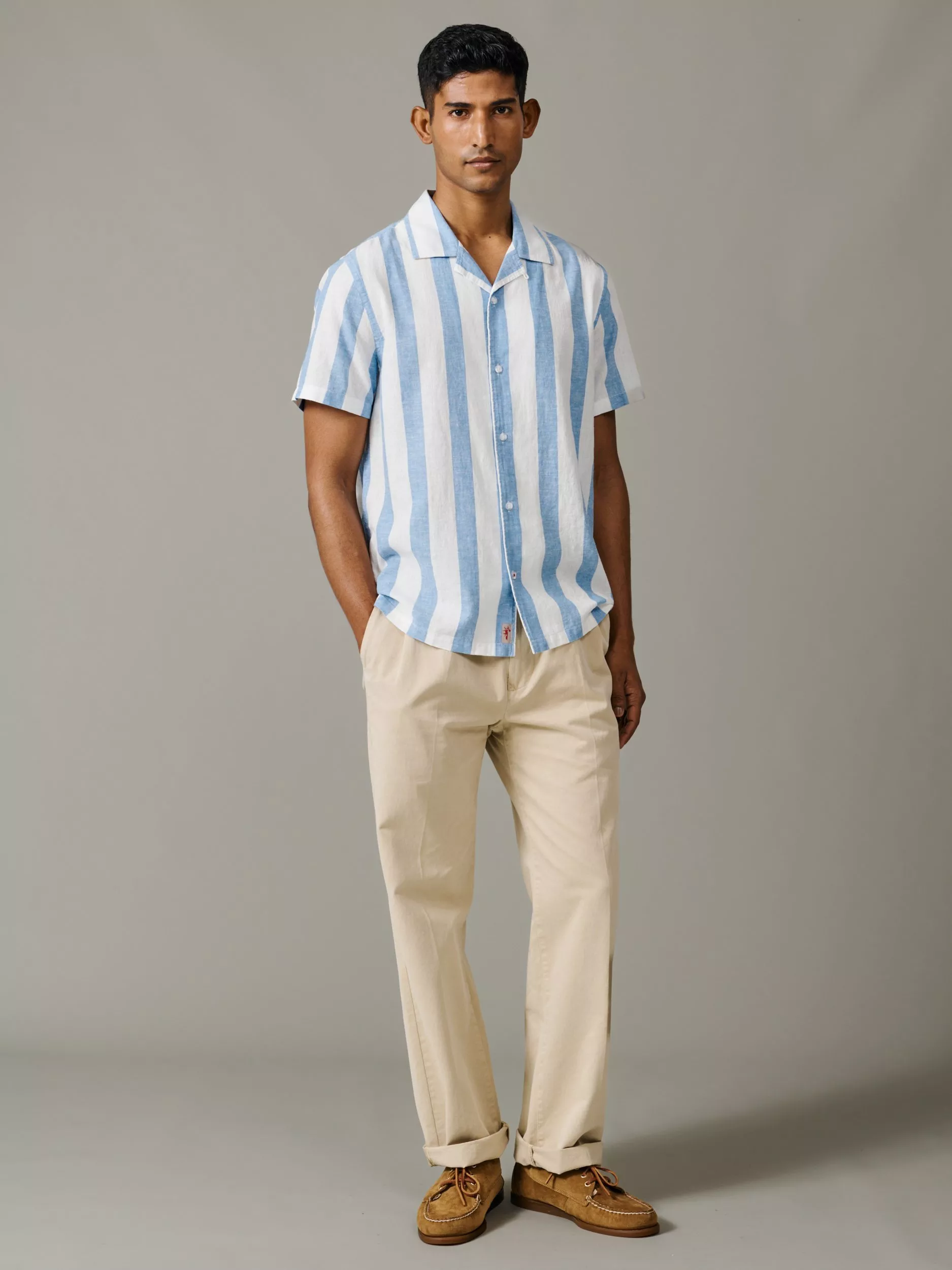Men’s summer outfit: model wearing blue and white striped short-sleeve shirt, beige chinos and tan loafers.