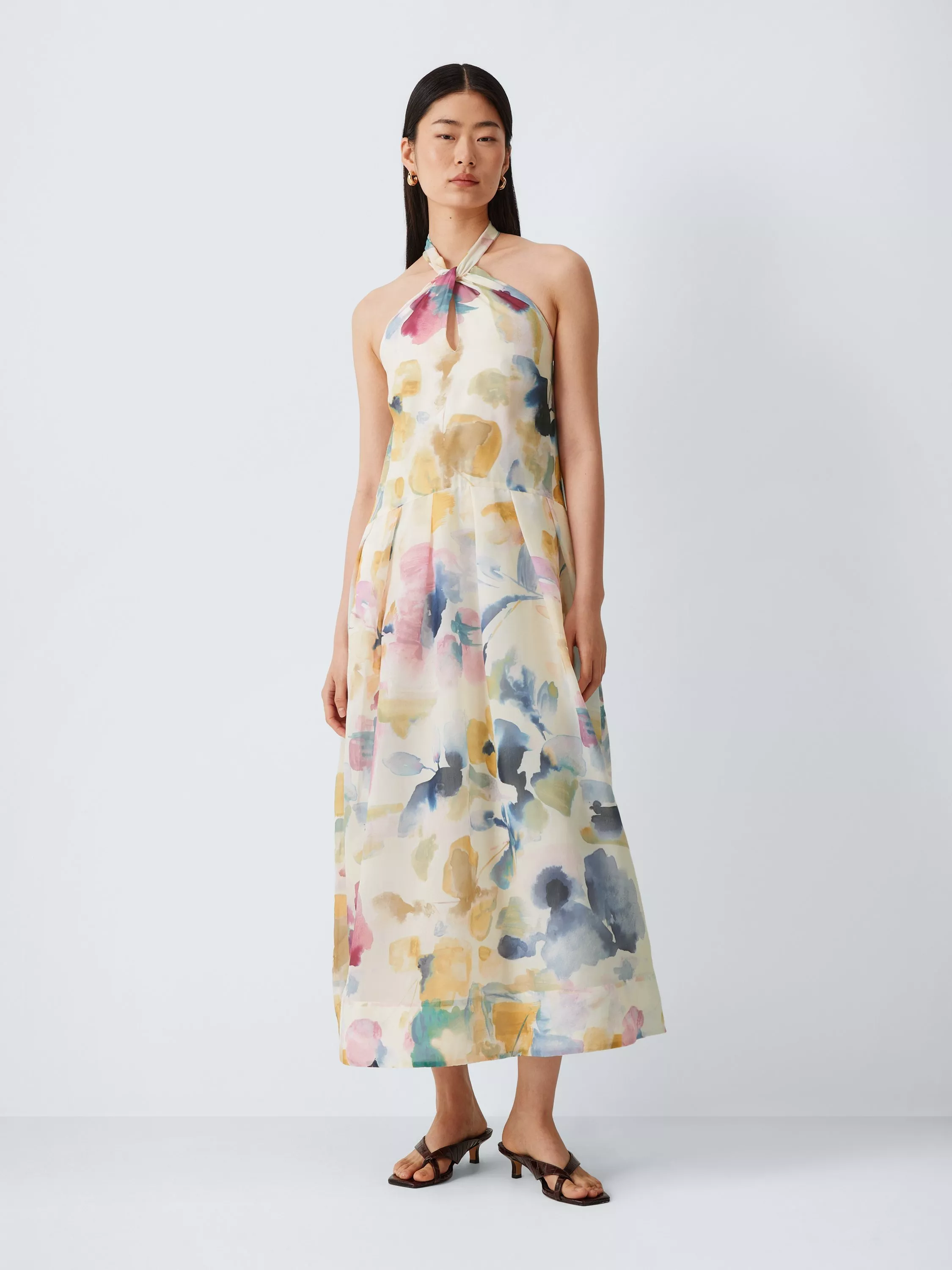 Model wearing a pastel floral halter-neck maxi dress with keyhole detail, styled with brown heeled sandals.