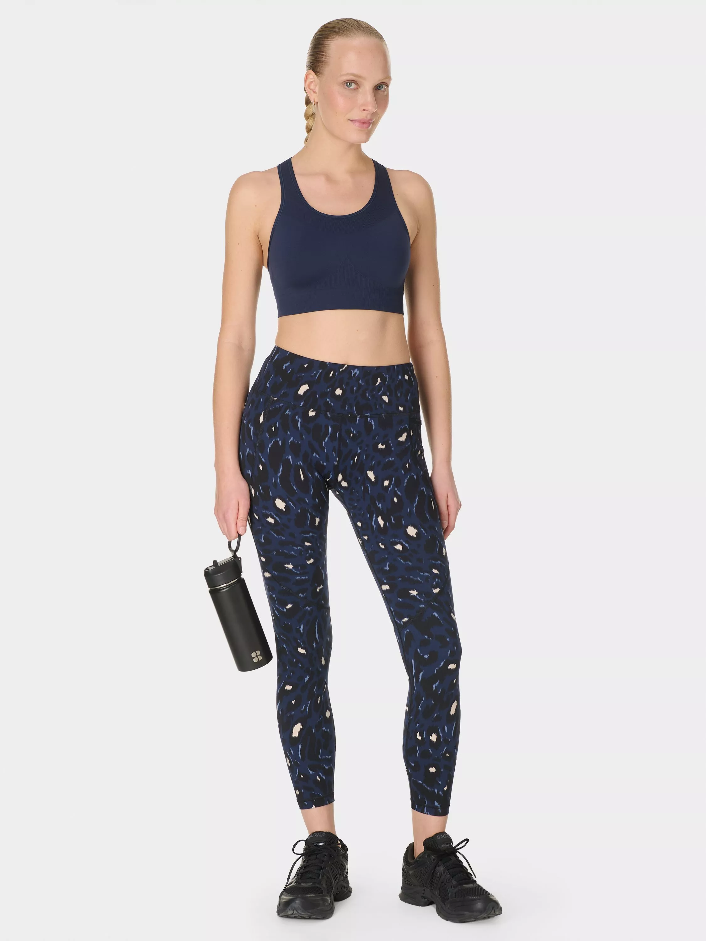 Woman in olive green activewear with white trim, posing confidently against a neutral background.