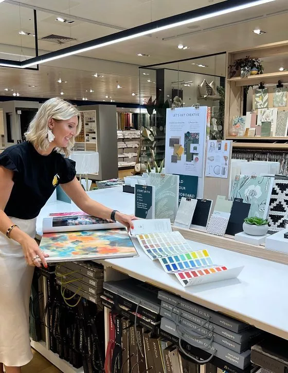 Person standing at a table with paint and material swatches