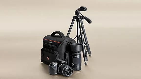 Sony camera kit with backpack, DSLR body, lenses and tripod on neutral background for photography gear setup