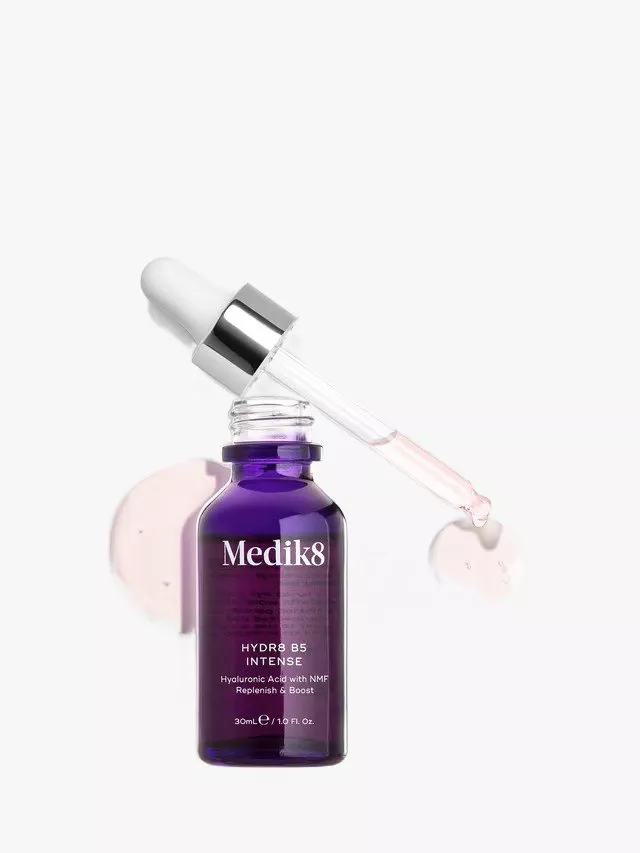A purple bottle of Medik8 HYDR8 B5 Intense serum with a silver dropper and pink liquid drops on a white background.