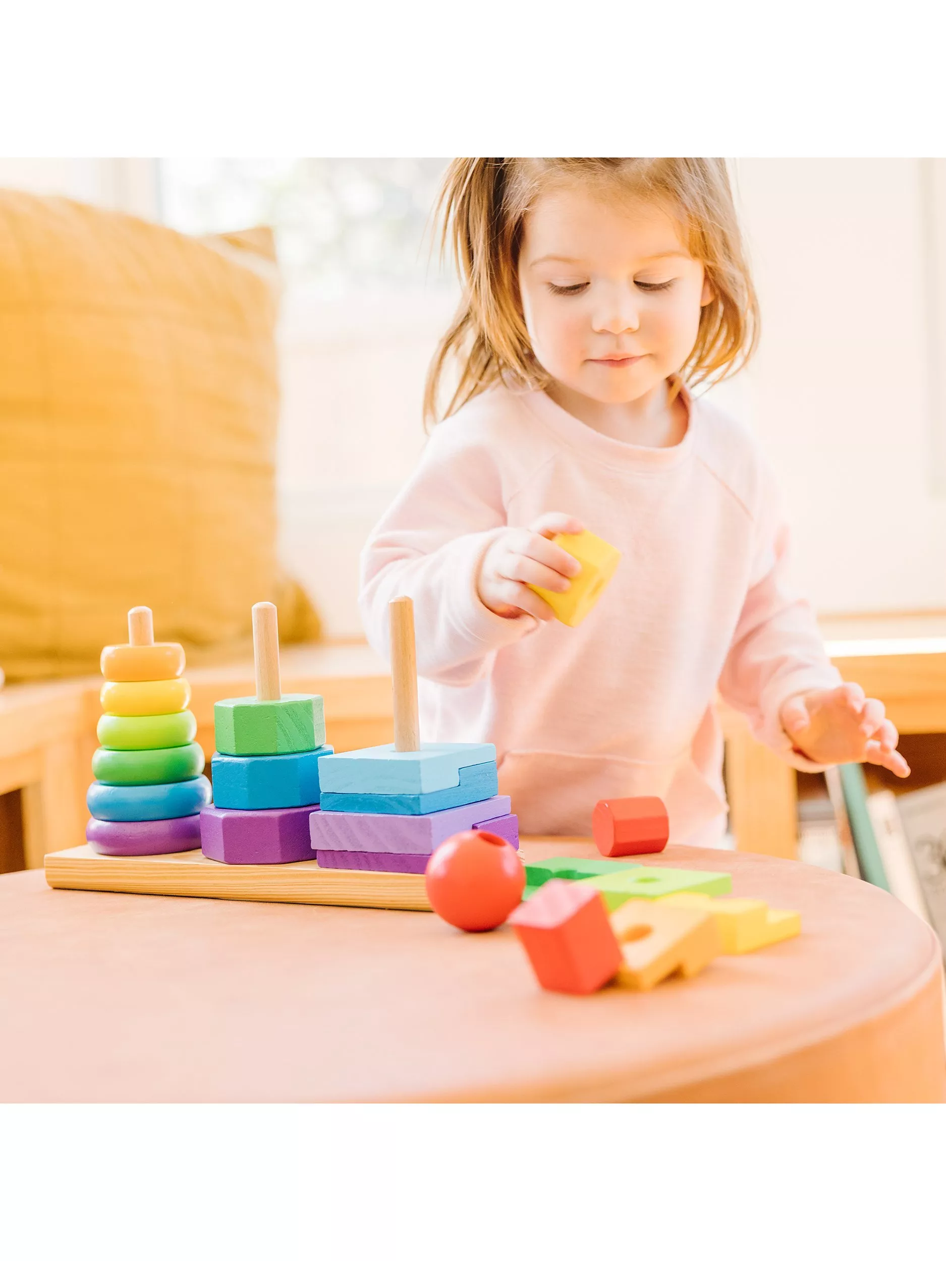 Toddler playing with a wooden stacking rings set