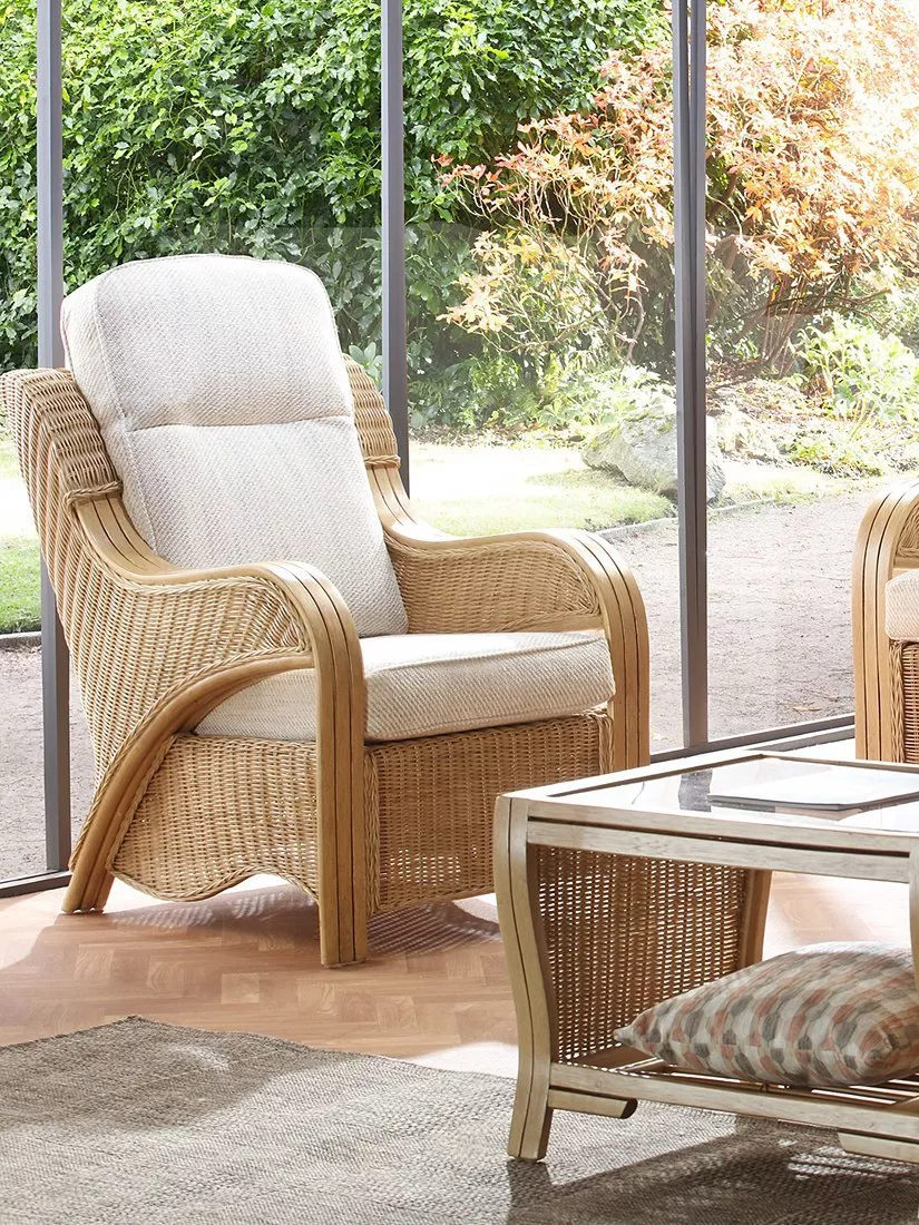 Light rattan conservatory furniture set with sofa, armchairs and coffee table in a sunlit garden room