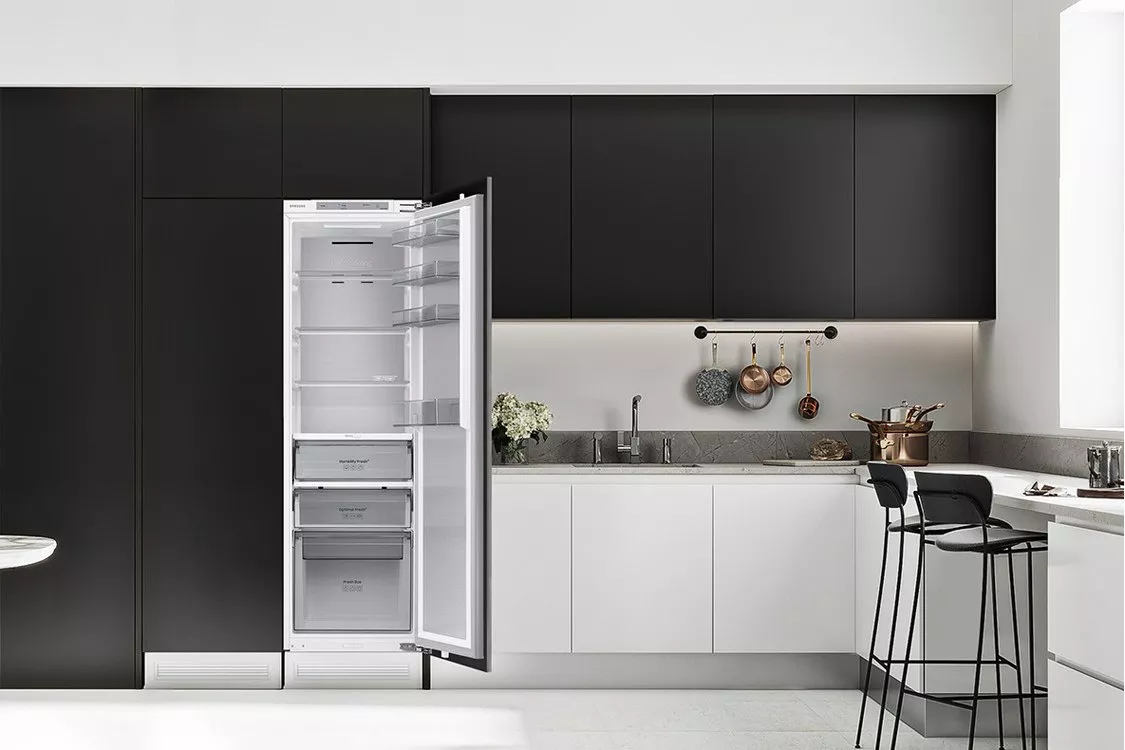 Modern minimalist kitchen with open integrated tall fridge freezer, matte black cabinets and white worktops