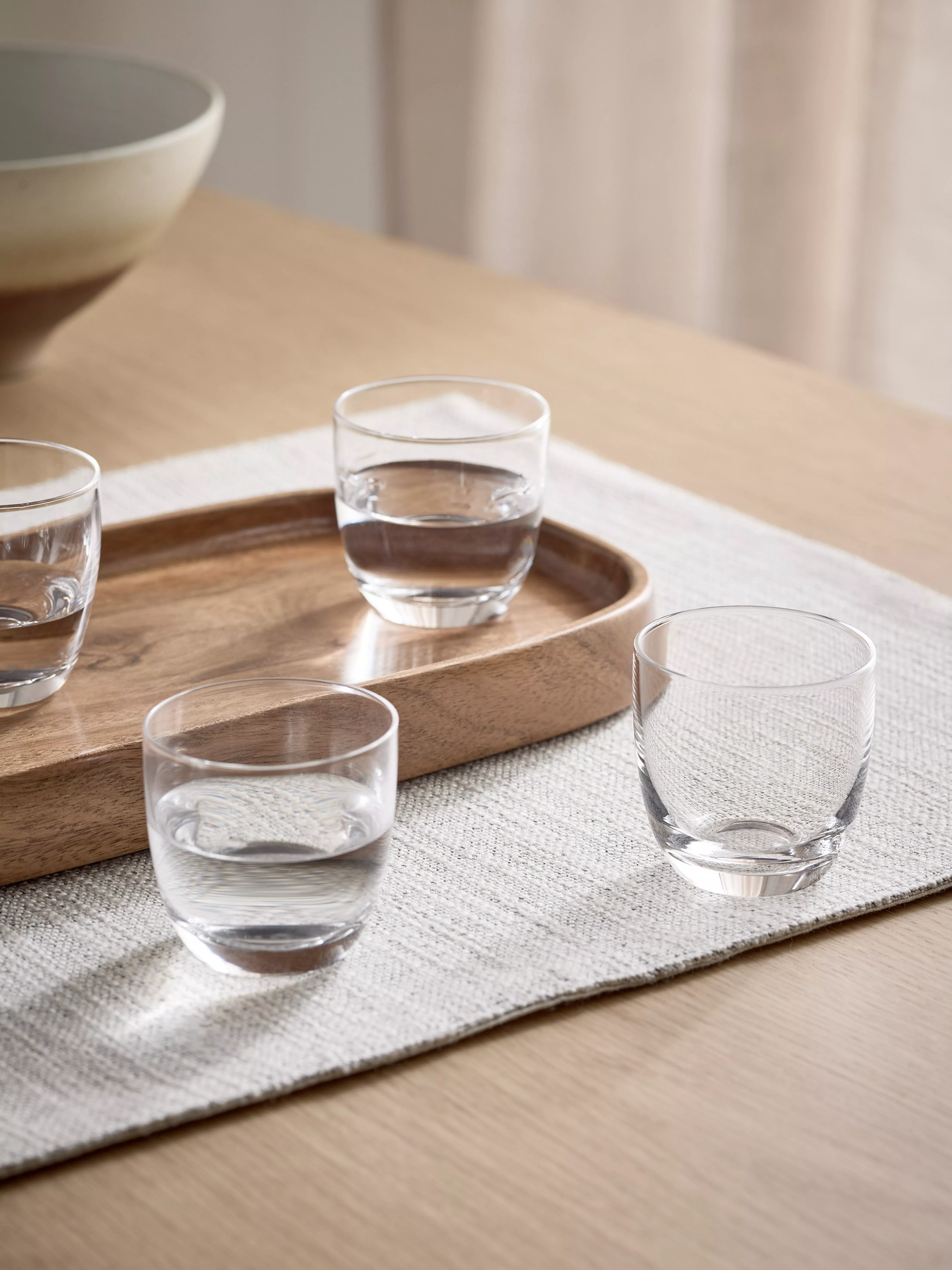 Vodka tasting set on marble table with shot glasses, wooden serving boards, and canapés in natural light
