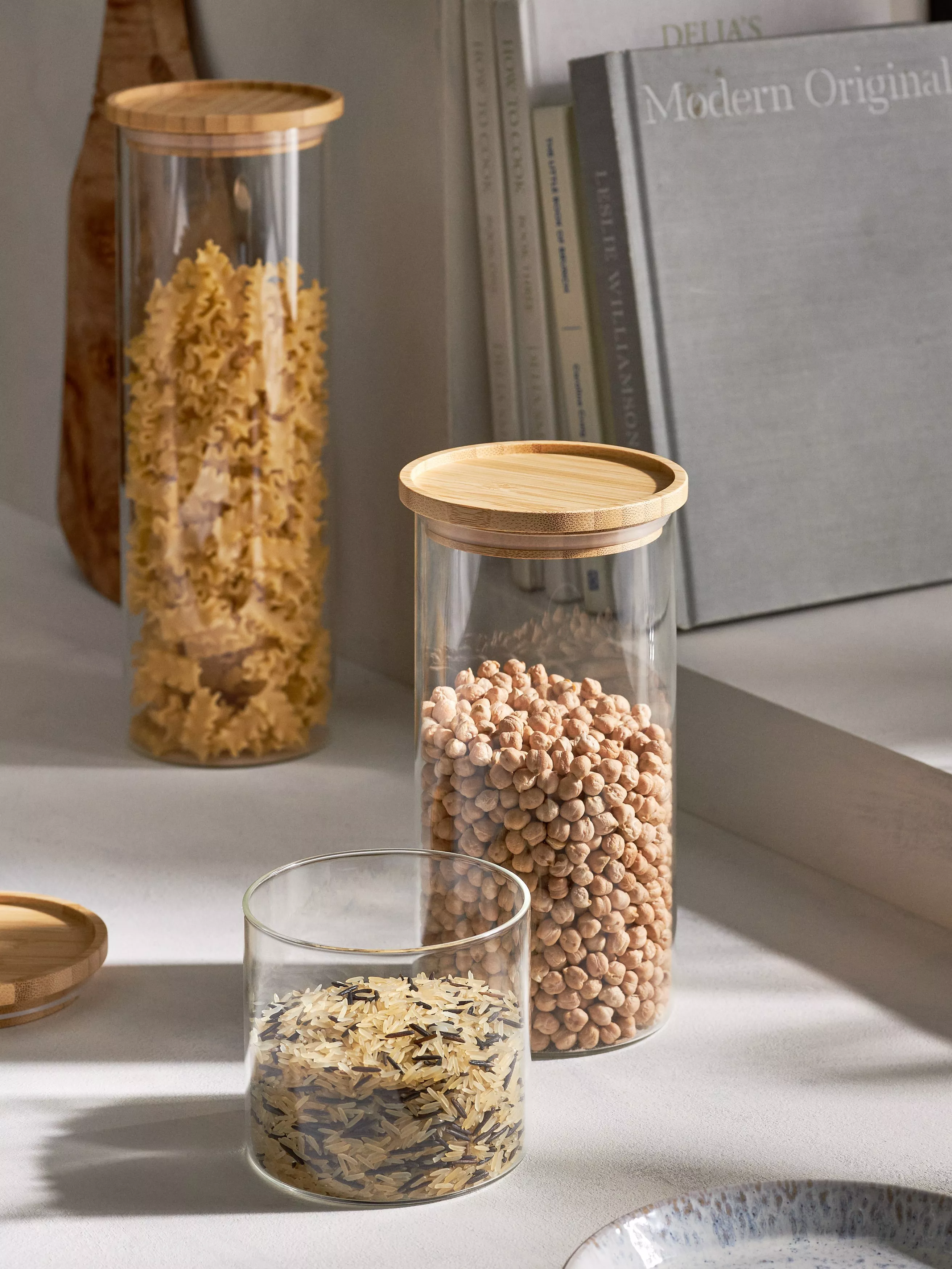 3 glass jars with wooden lids filled with pasta varieties