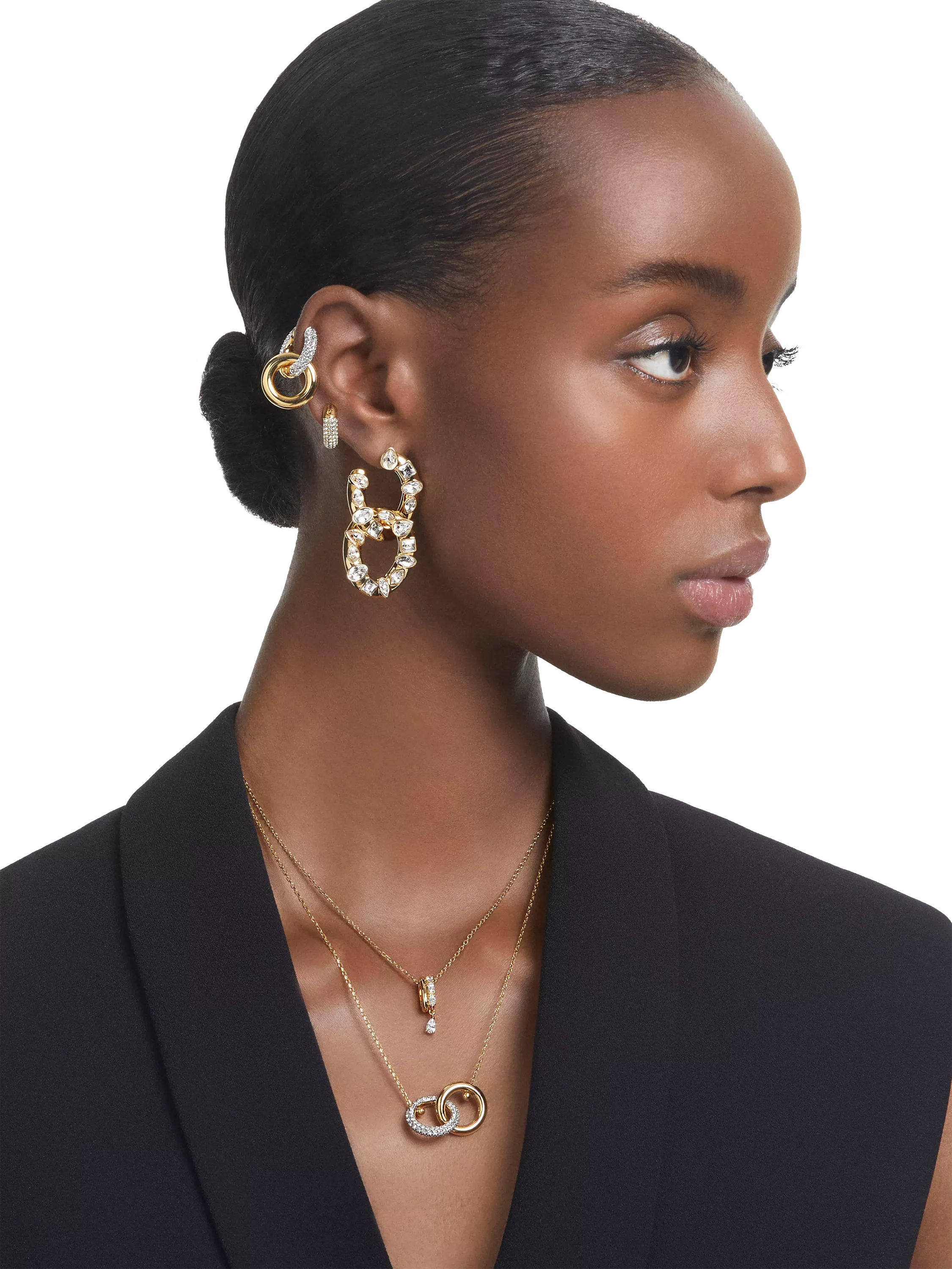 Person with big diamond and gold hoop earrings, matching ear cuff and necklaces