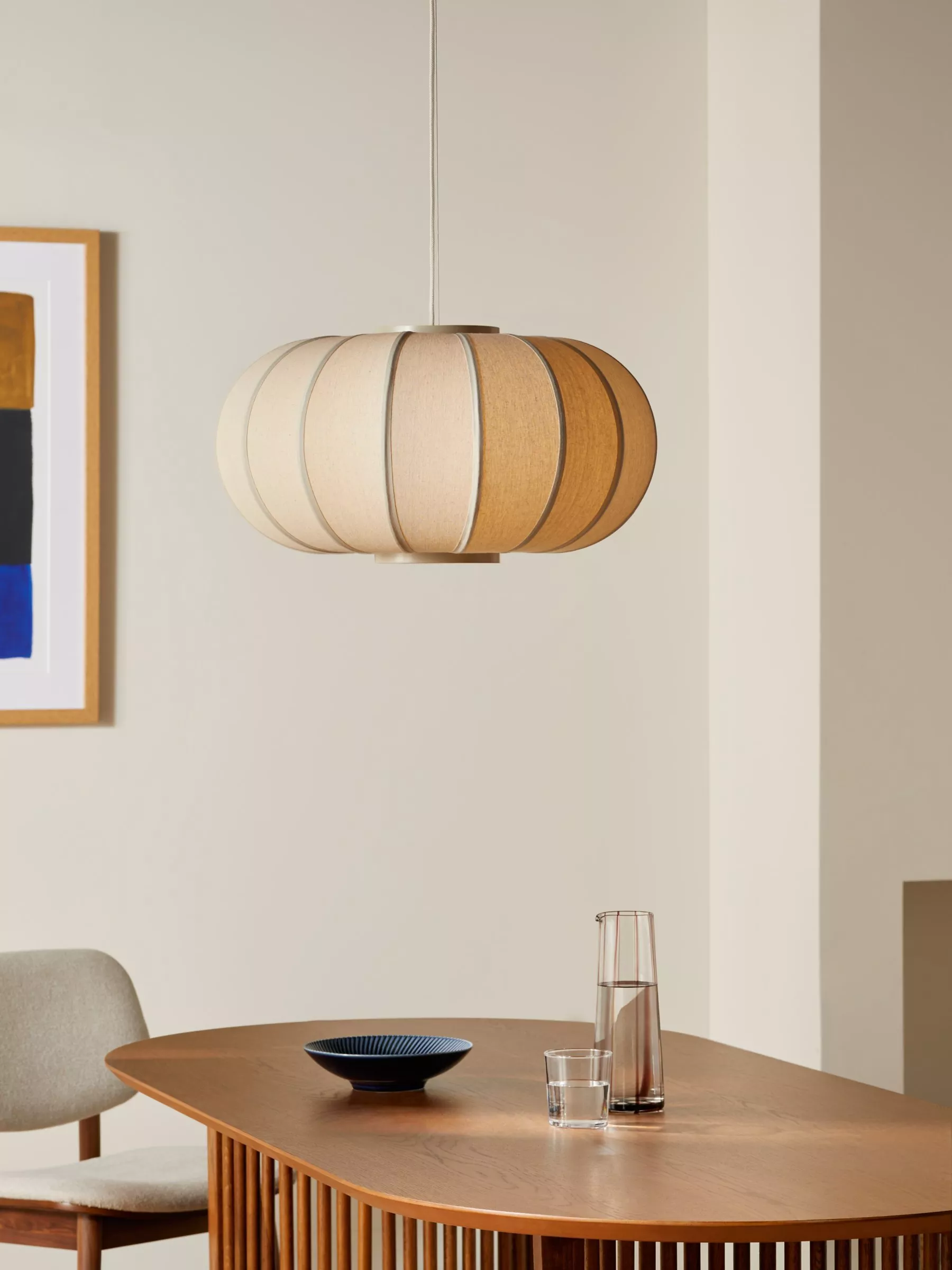 Modern fabric pendant ceiling light above wooden dining table in minimalist dining room interior setting