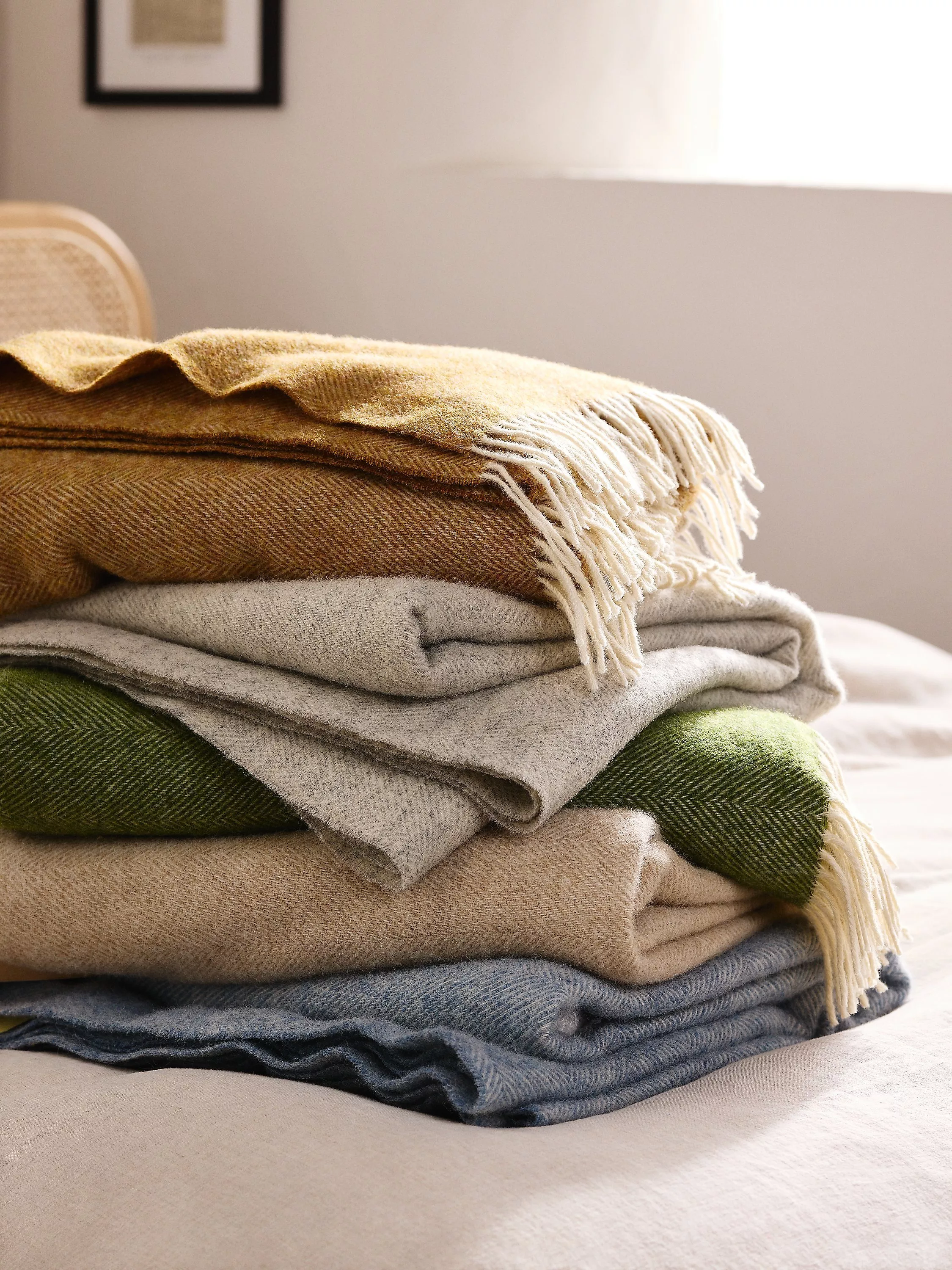 A pile of cream, yellow, beige and navy blankets 