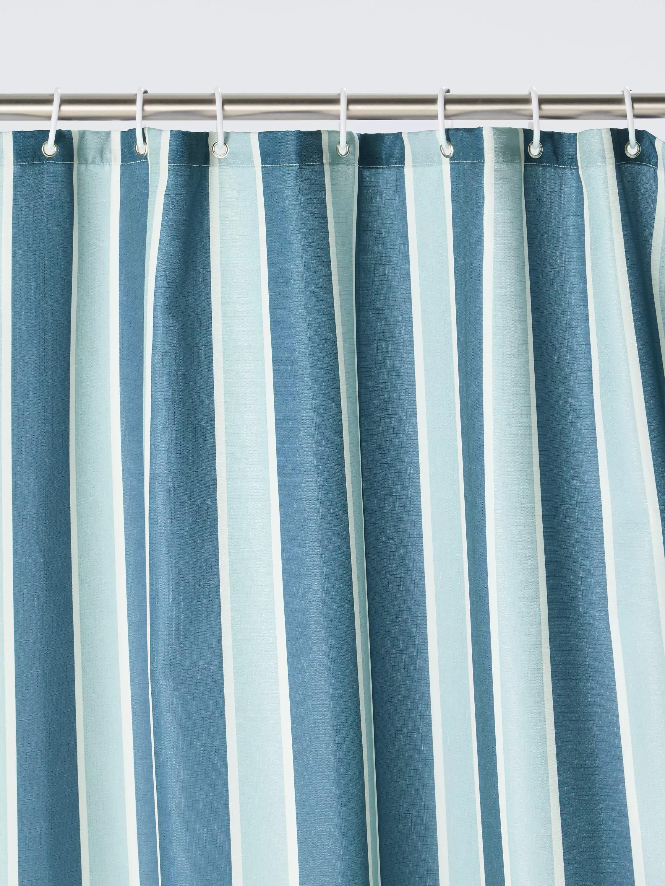 Green and white striped shower curtain on metal rail with hooks, modern bathroom décor textile close-up