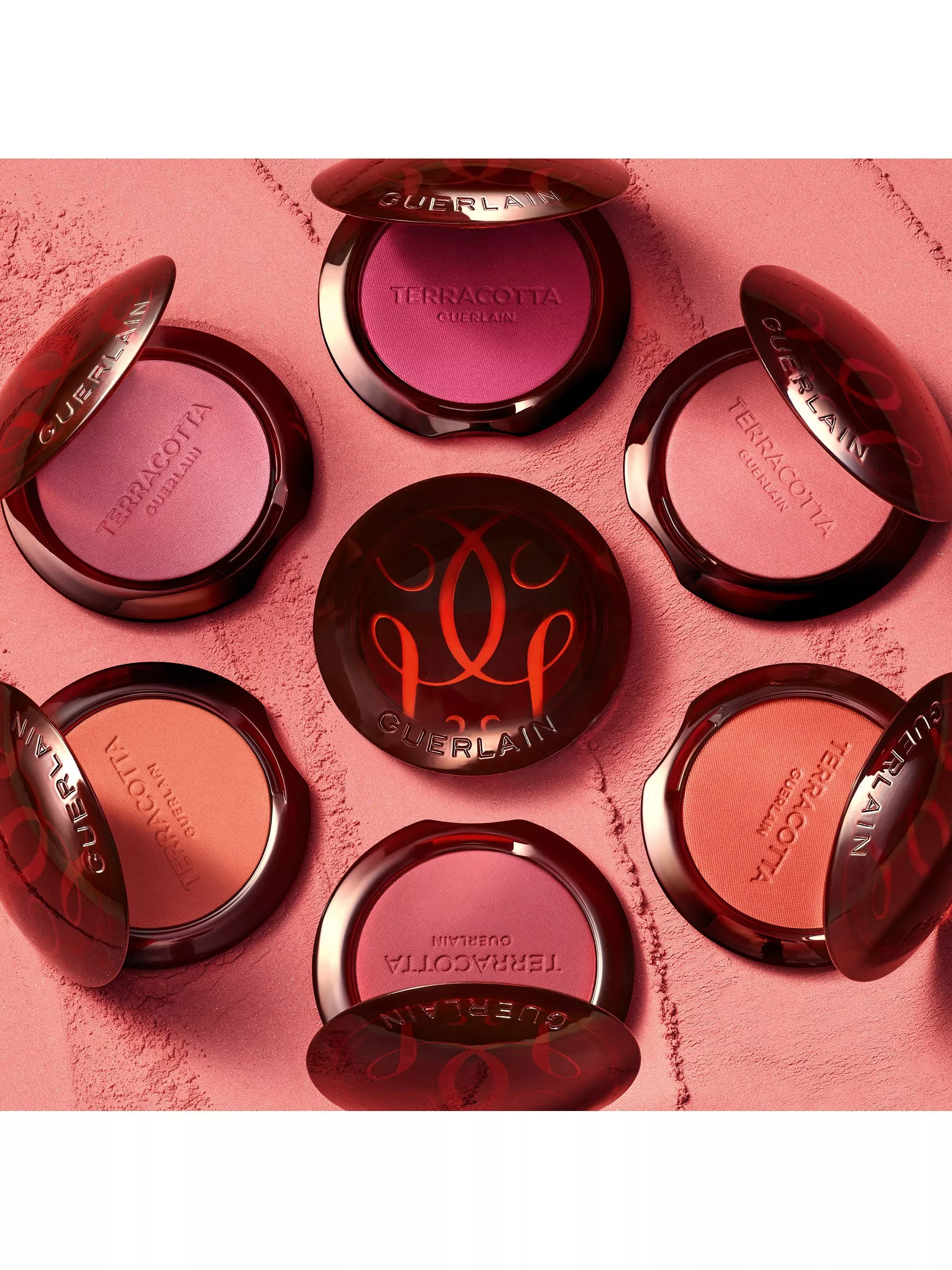Open rose-gold compact cream blushes in pink and coral shades on a vibrant magenta background, close-up
