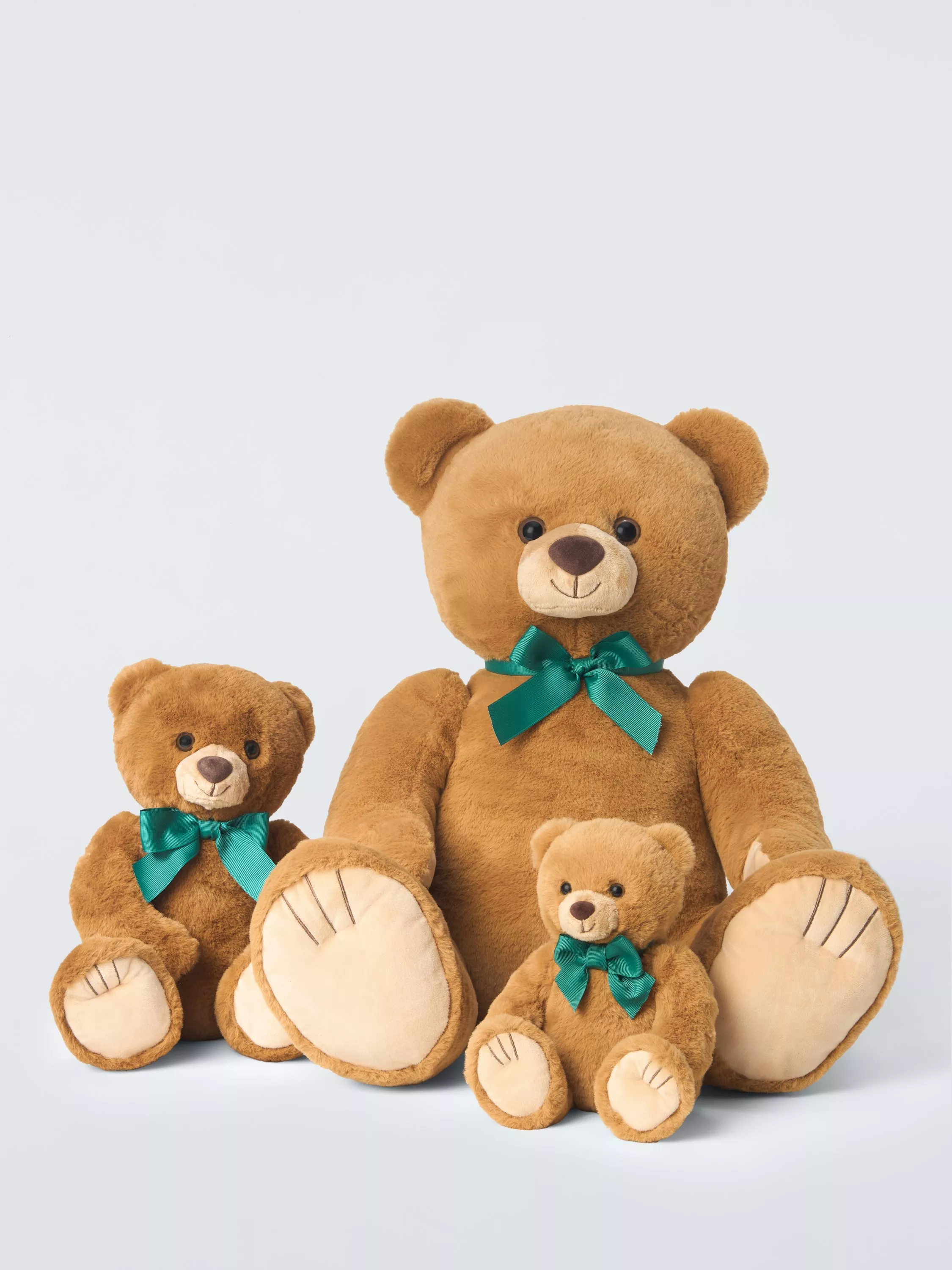 Three brown teddy bears with teal bows, soft plush toys in different sizes on a light background