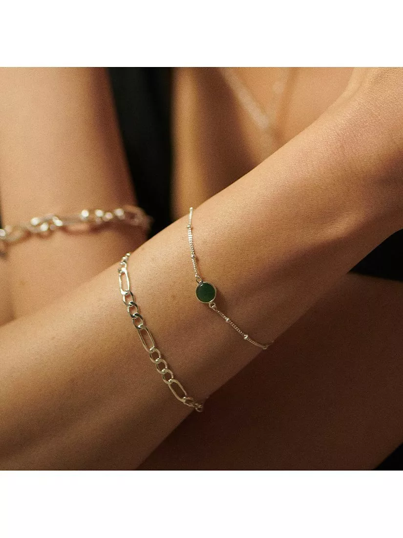 Wrist with gold chain bracelet and gold bracelet with green stone