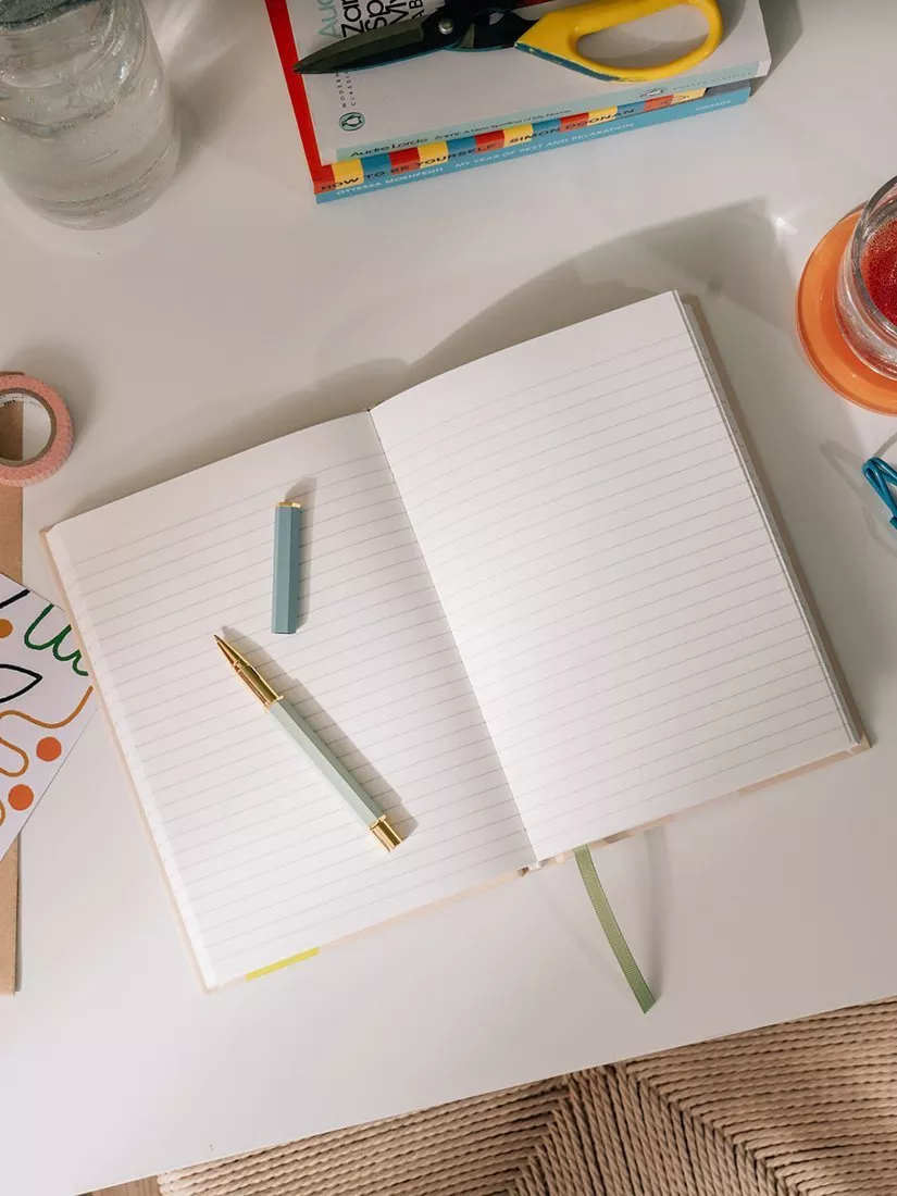 Purple floral notebook beside matching pens 