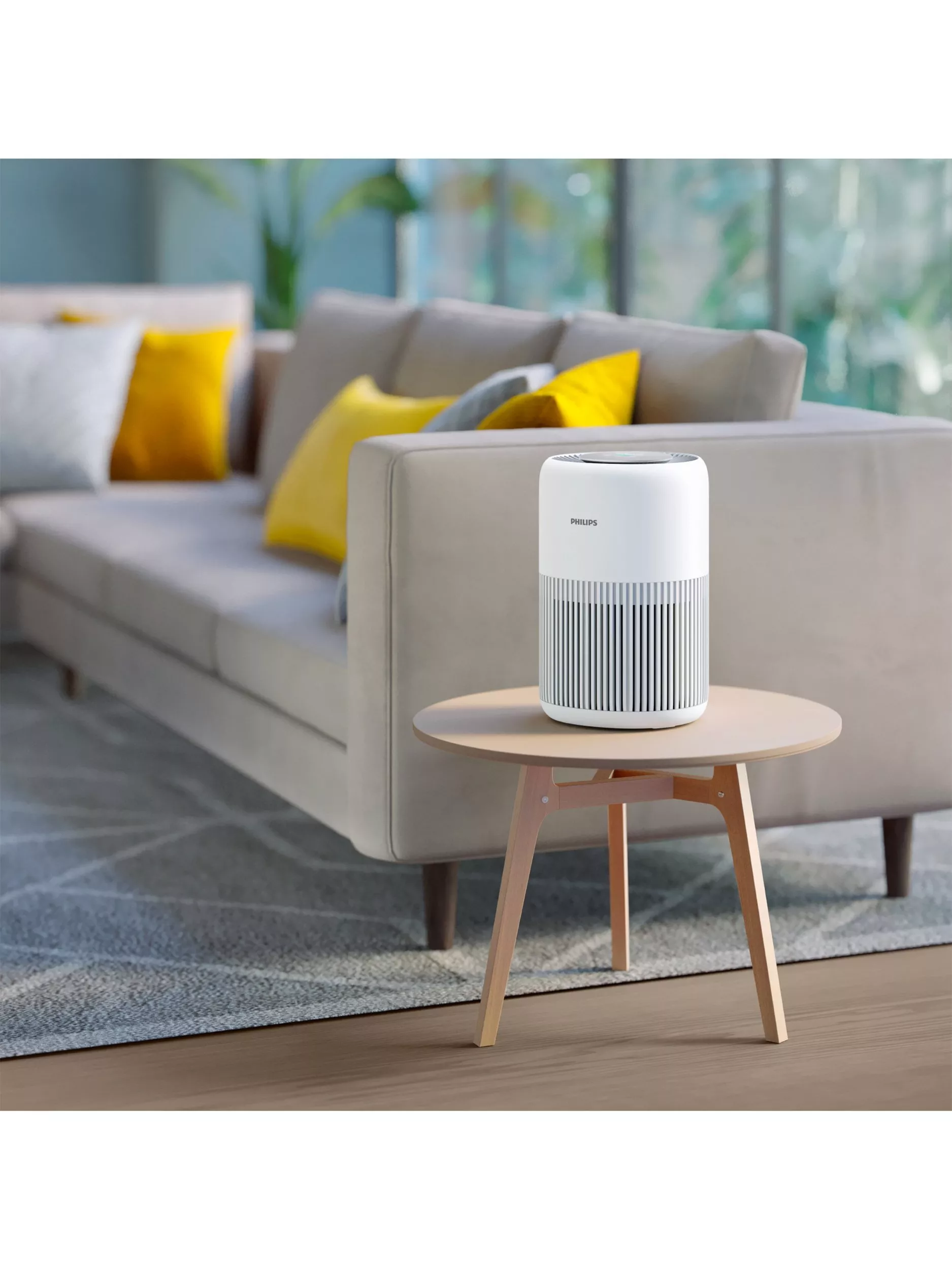 A modern living room with a grey sofa and yellow cushions. A white air purifier sits on a wooden table.