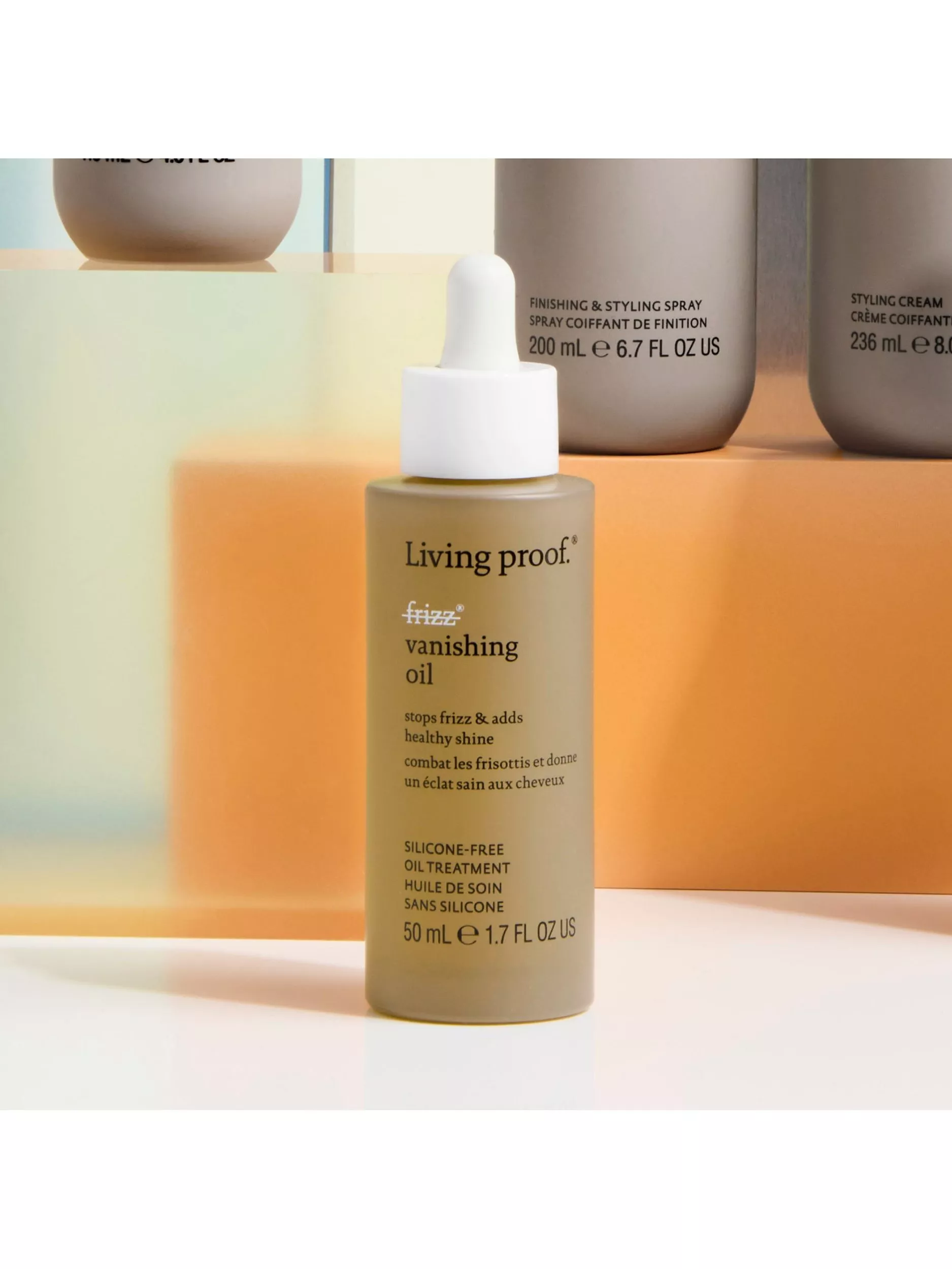 Hair oil bottle with a dropper cap, promising to reduce frizz and add shine, displayed on a colourful background.