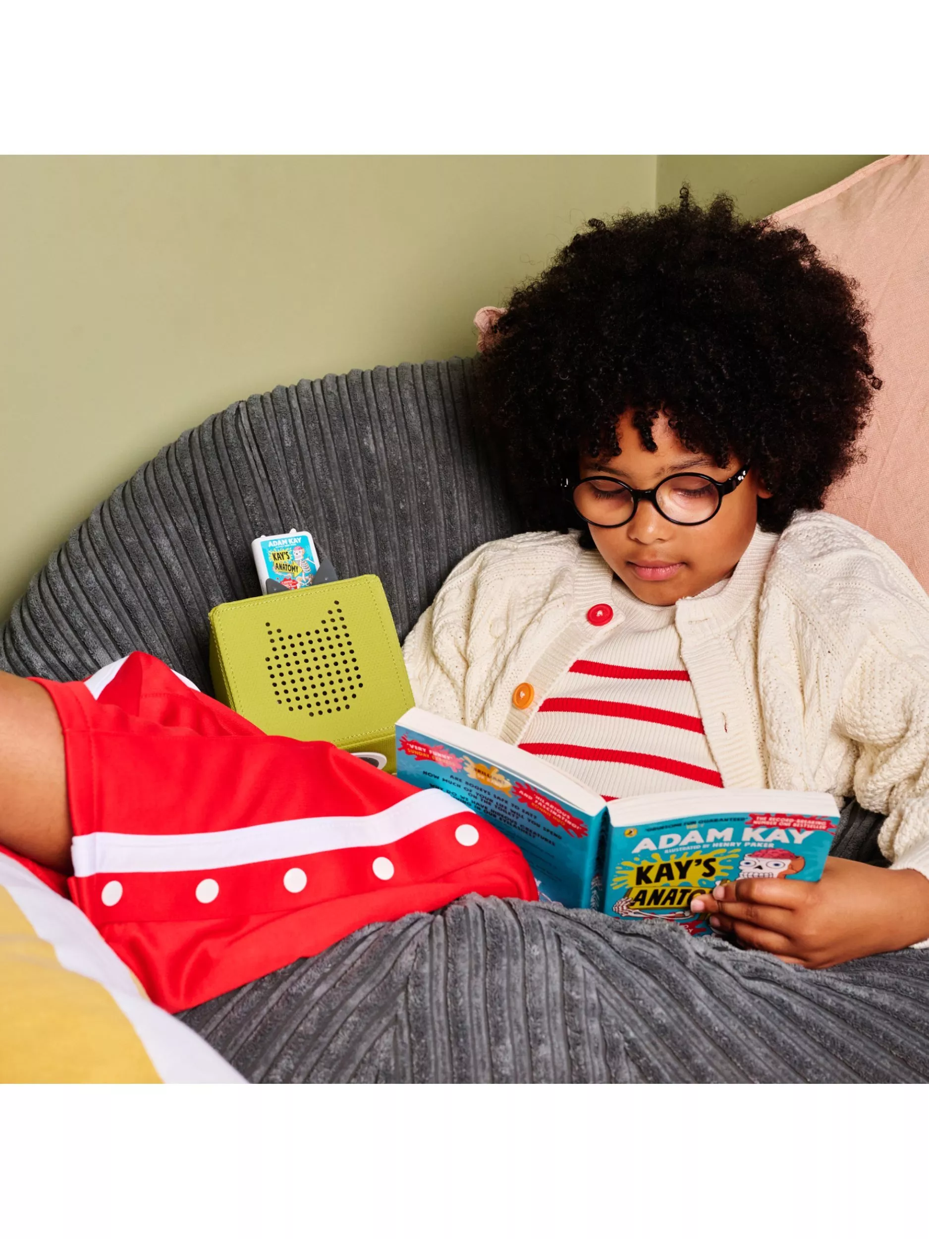 Young girl reading her book alongside to listening to the story of it on her audio player