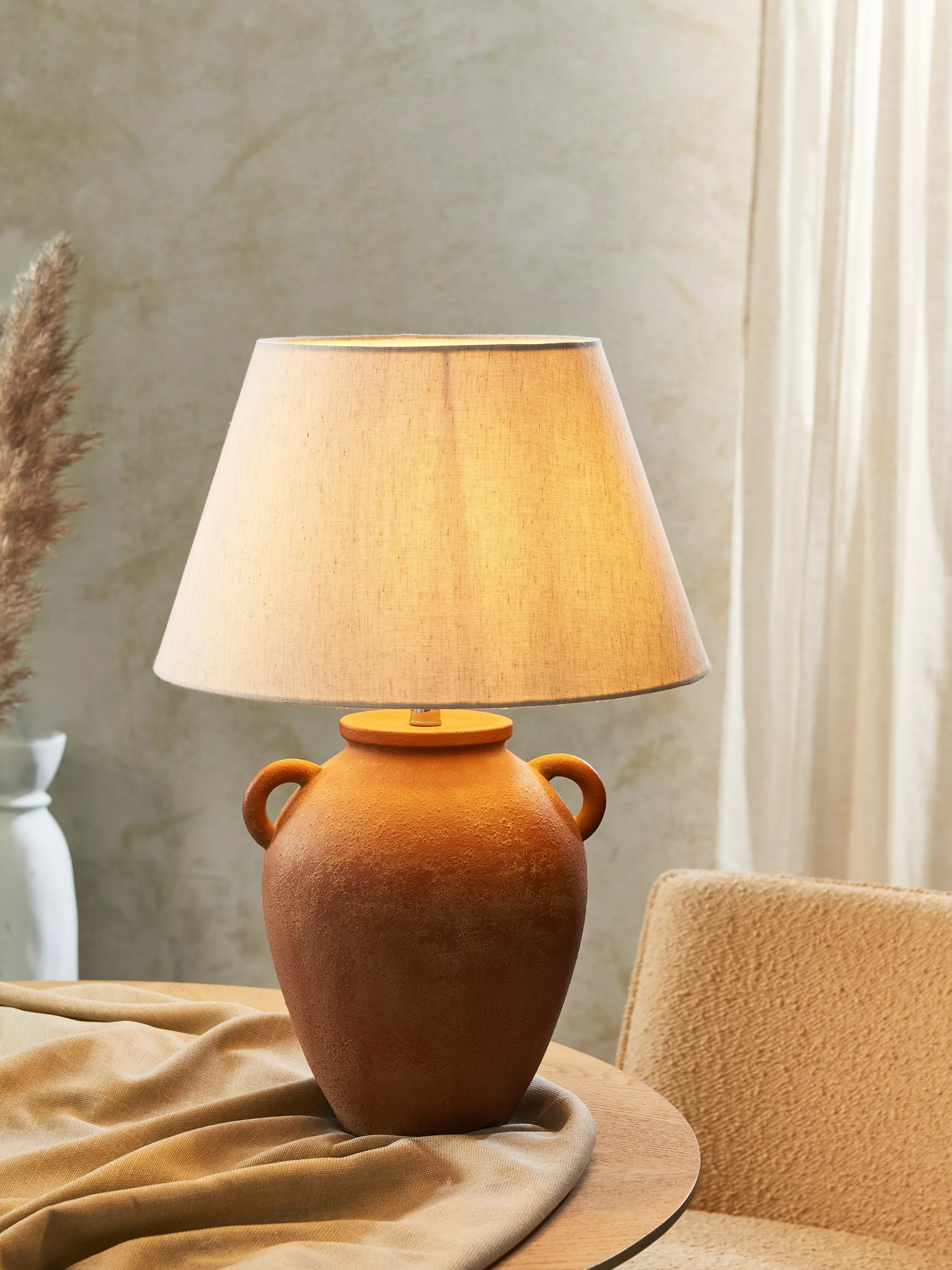 Modern lamp with a geometric shade on books, atop a wooden table, creating a cosy, stylish ambience in a minimalist room.