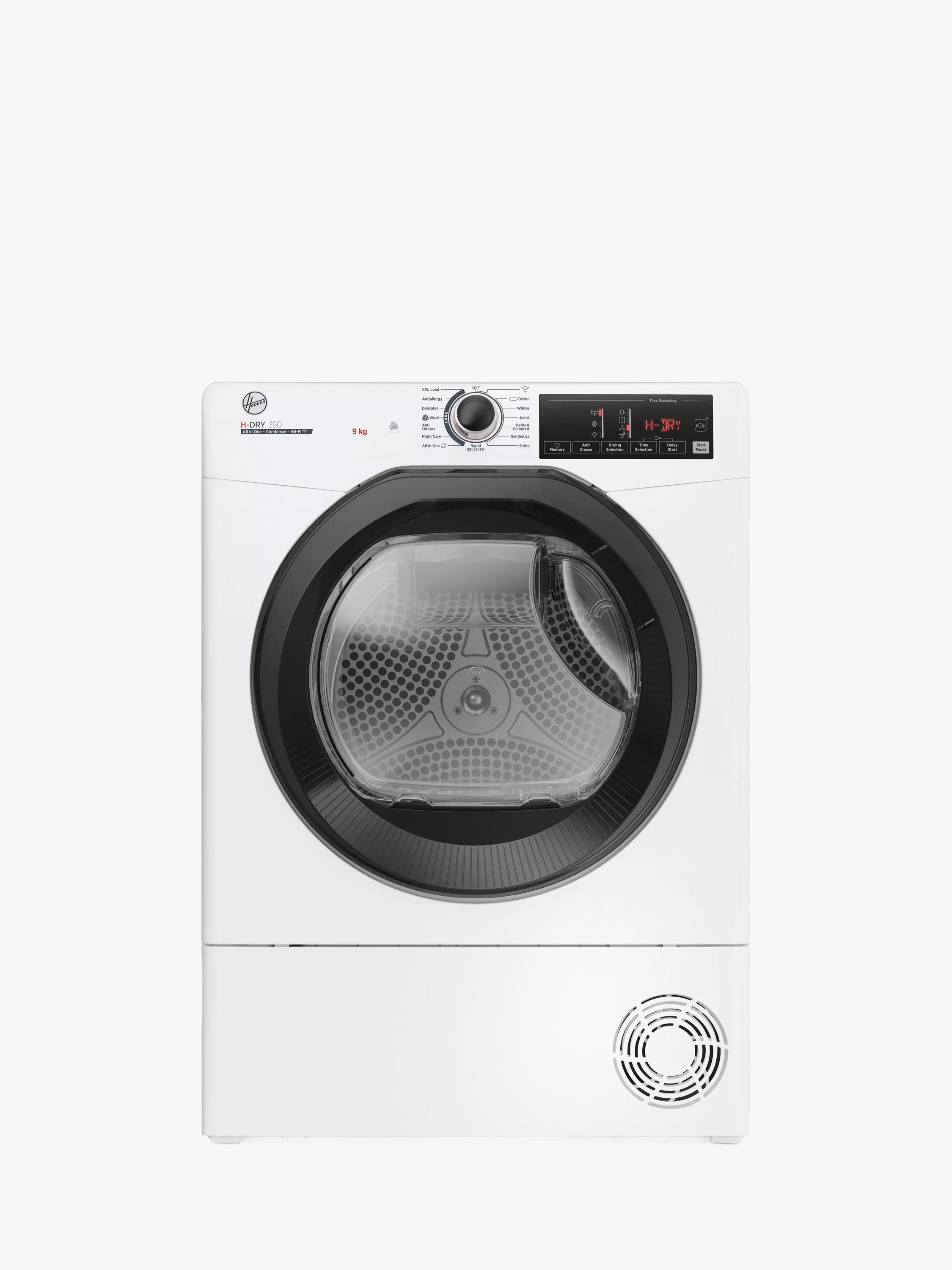 Man kneeling beside modern front-loading washing machine in stylish laundry room, selecting programme on display panel