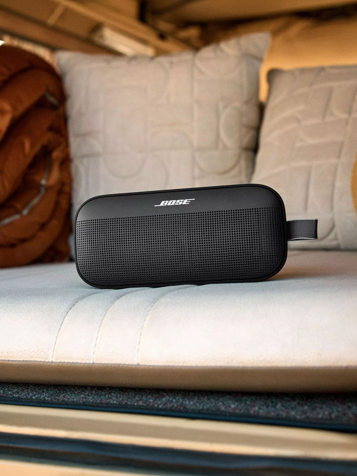 Bose portable Bluetooth speaker on a bed in a camper van, ideal for travel, camping and wireless music
