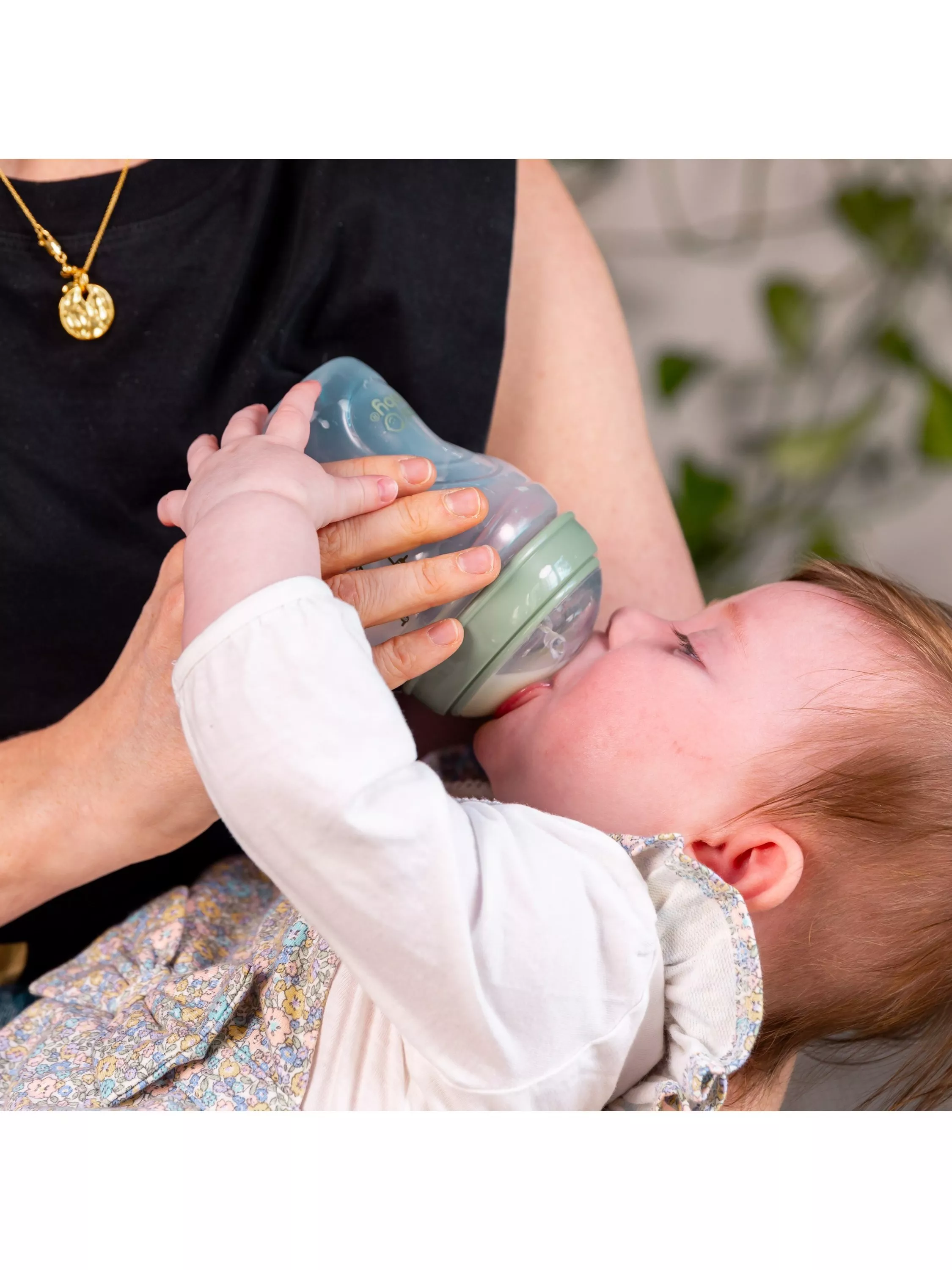 Close-up of a baby drinking from a bottle in a parent’s arms, gentle feeding and childcare at home